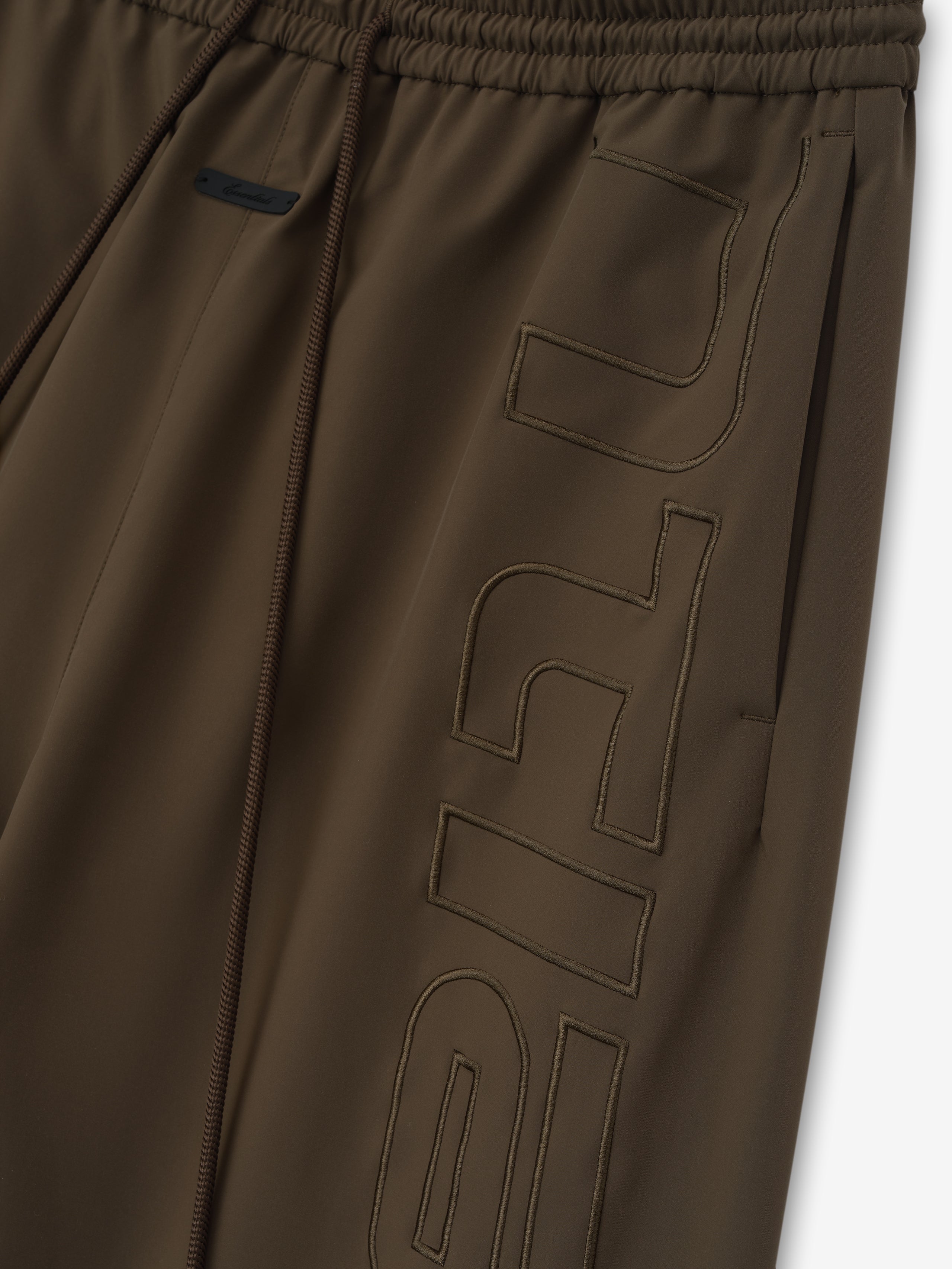 close-up of brown polyester women's track pants with elastic waistband and tonal stitched branding detail on leg