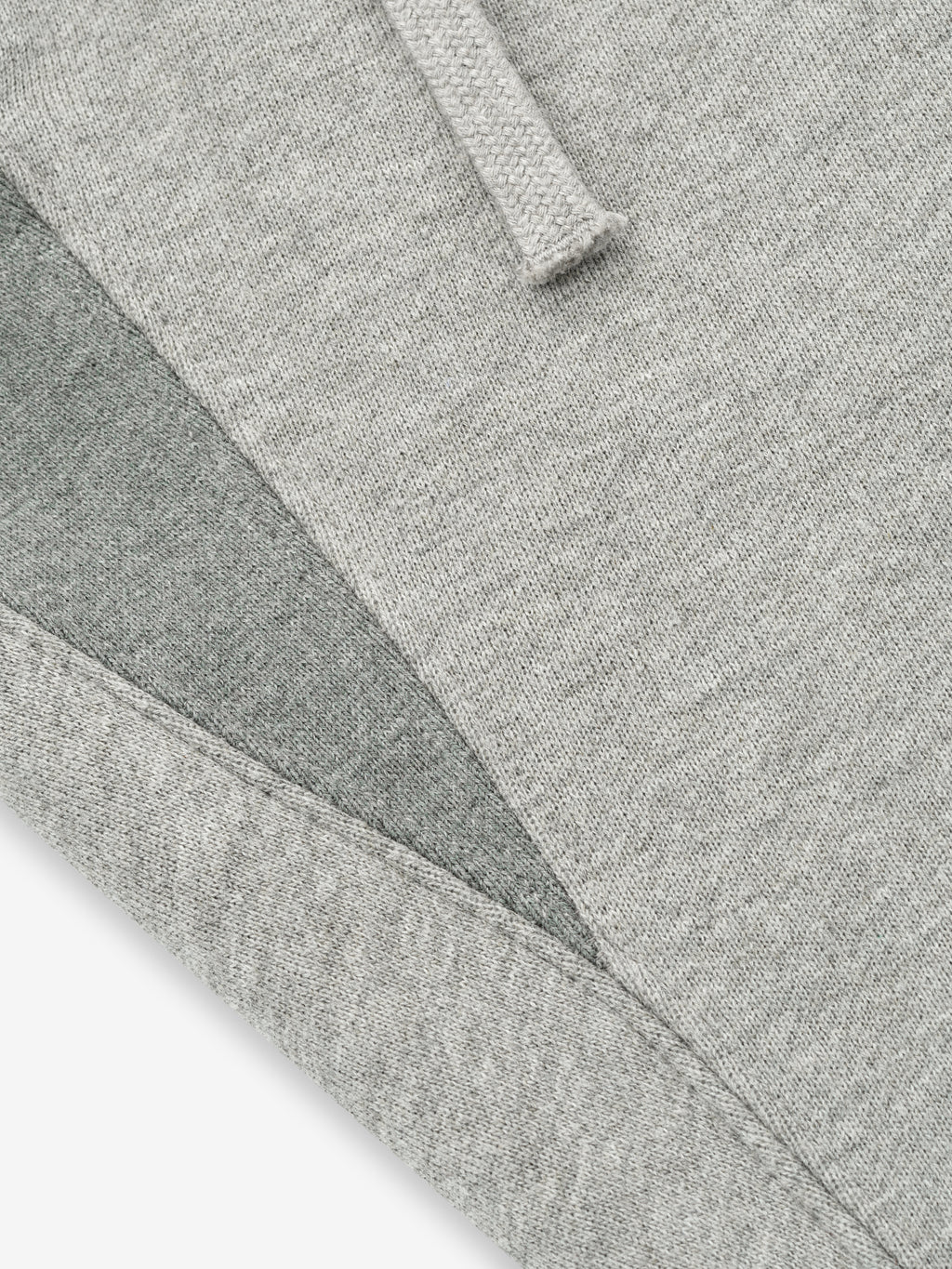 close-up of light grey core fleece fabric with stitched edges and drawstring detail on sweatpants