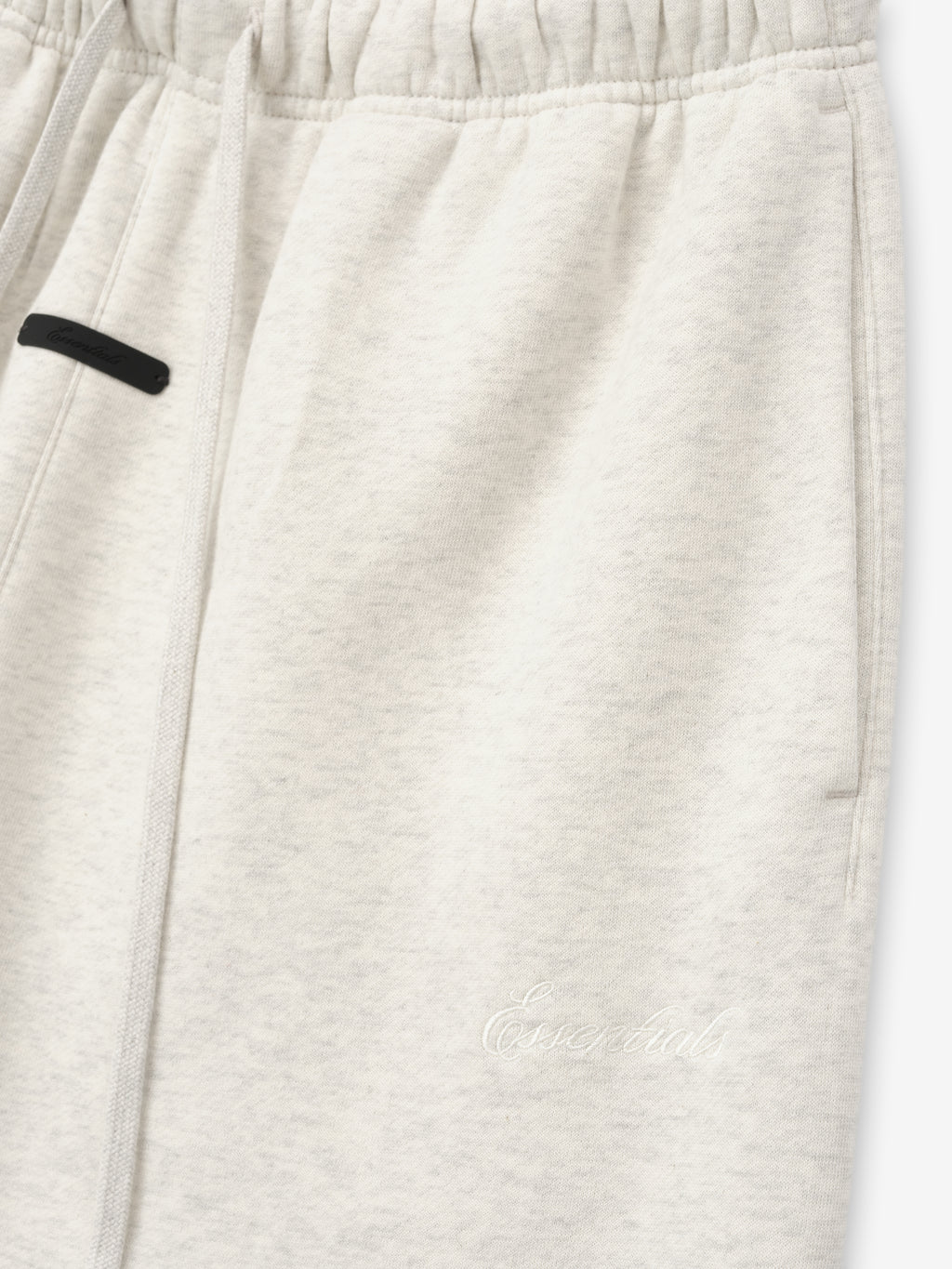 close-up of off-white relaxed flare sweatpants with elastic waistband and tonal Essentials embroidered logo on leg