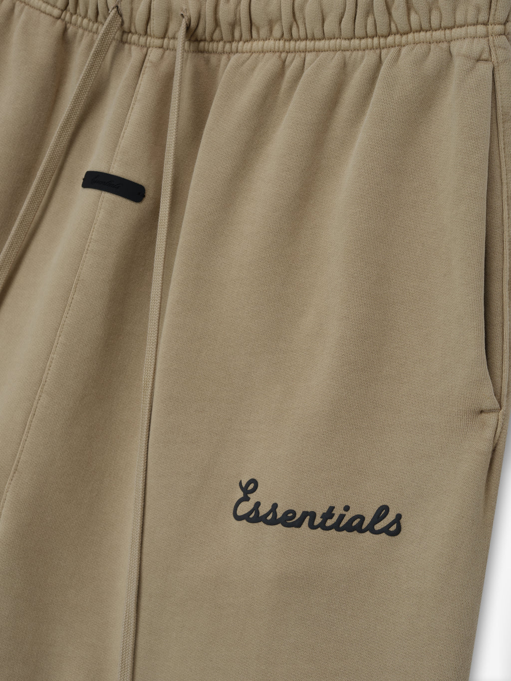 Beige pants with 'Essentials' puff print logo on a white background