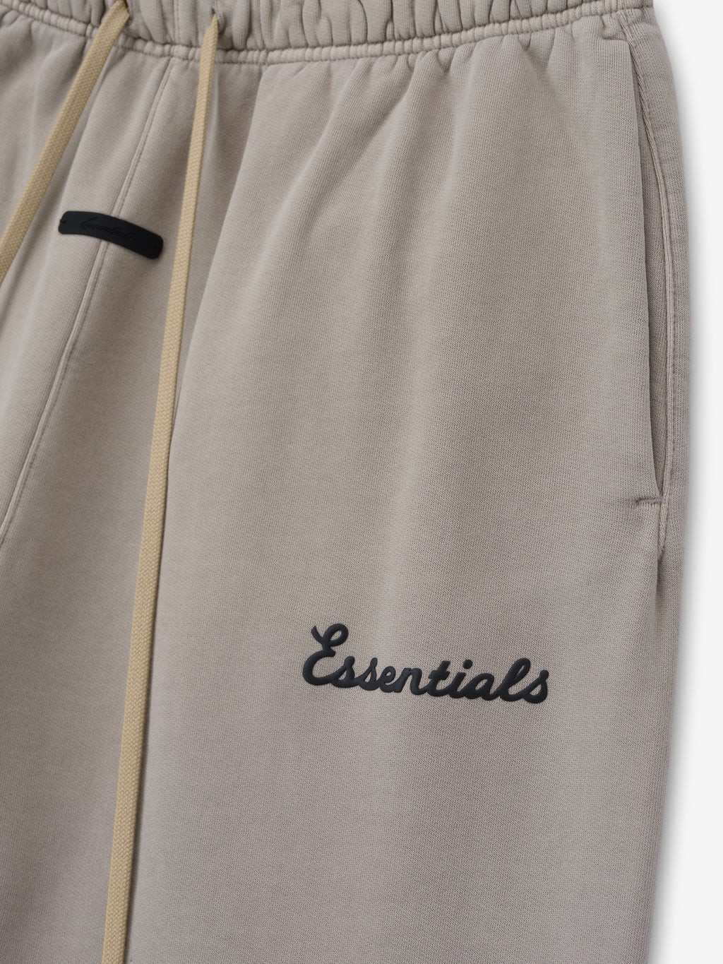Grey sweatpants with 'essentials' embroidery on a white background