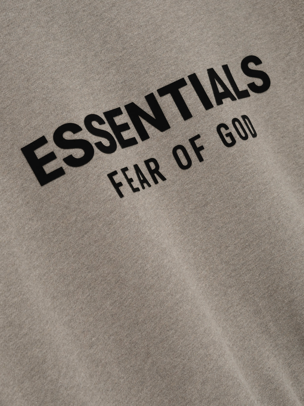 Close-up of taupe Classic Crewneck Sweatshirt with black ESSENTIALS Fear of God logo printed on front chest