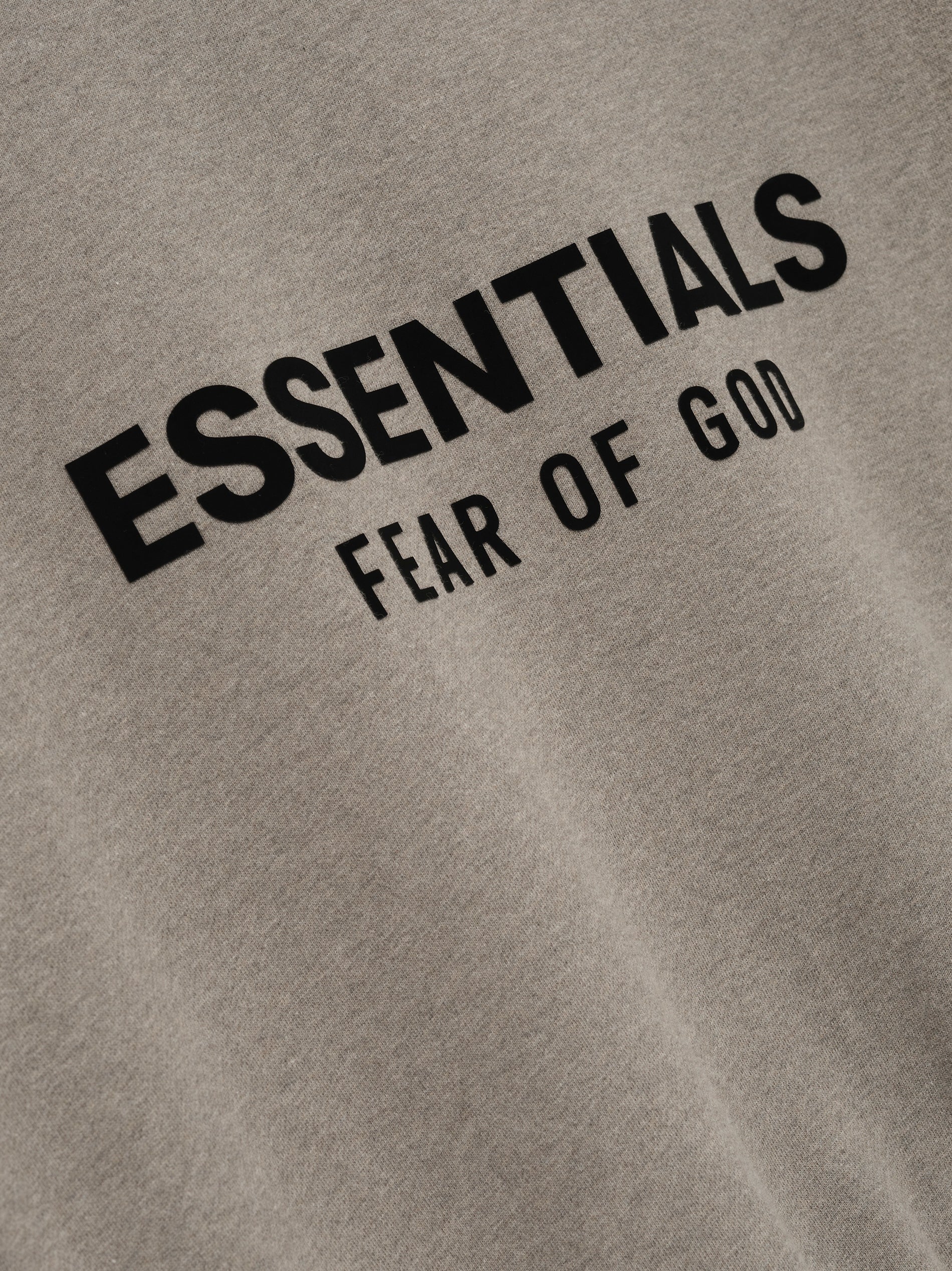 Close-up of taupe Classic Crewneck Sweatshirt with black ESSENTIALS Fear of God logo printed on front chest