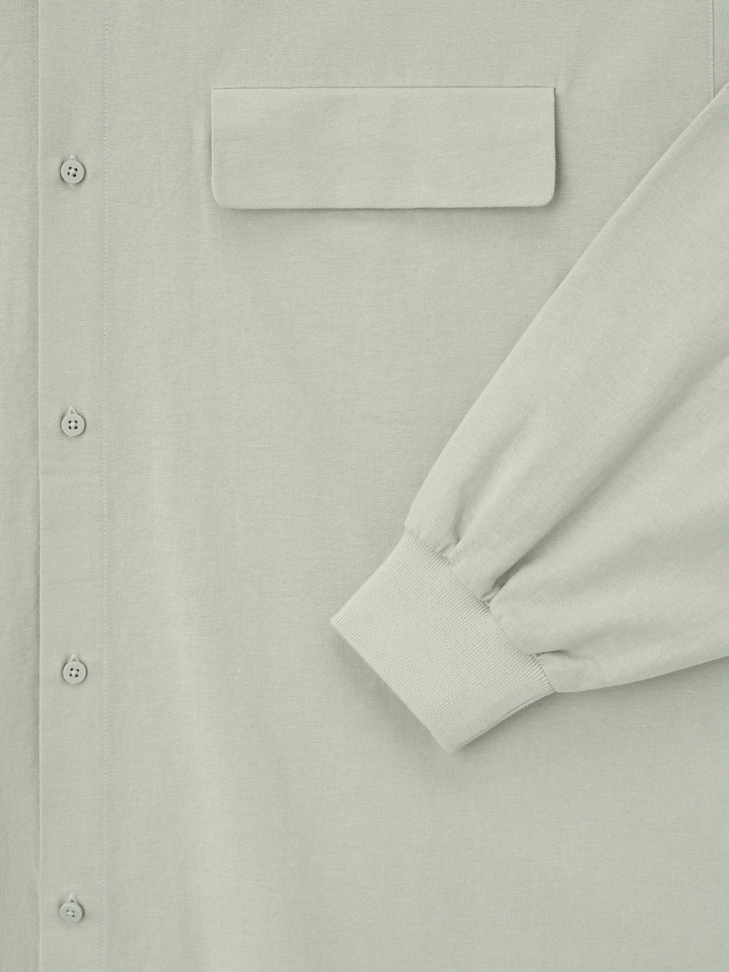 close-up of light sage oversized Oxford shirt with flap chest pocket, button front, and ribbed cuff on long sleeve detail
