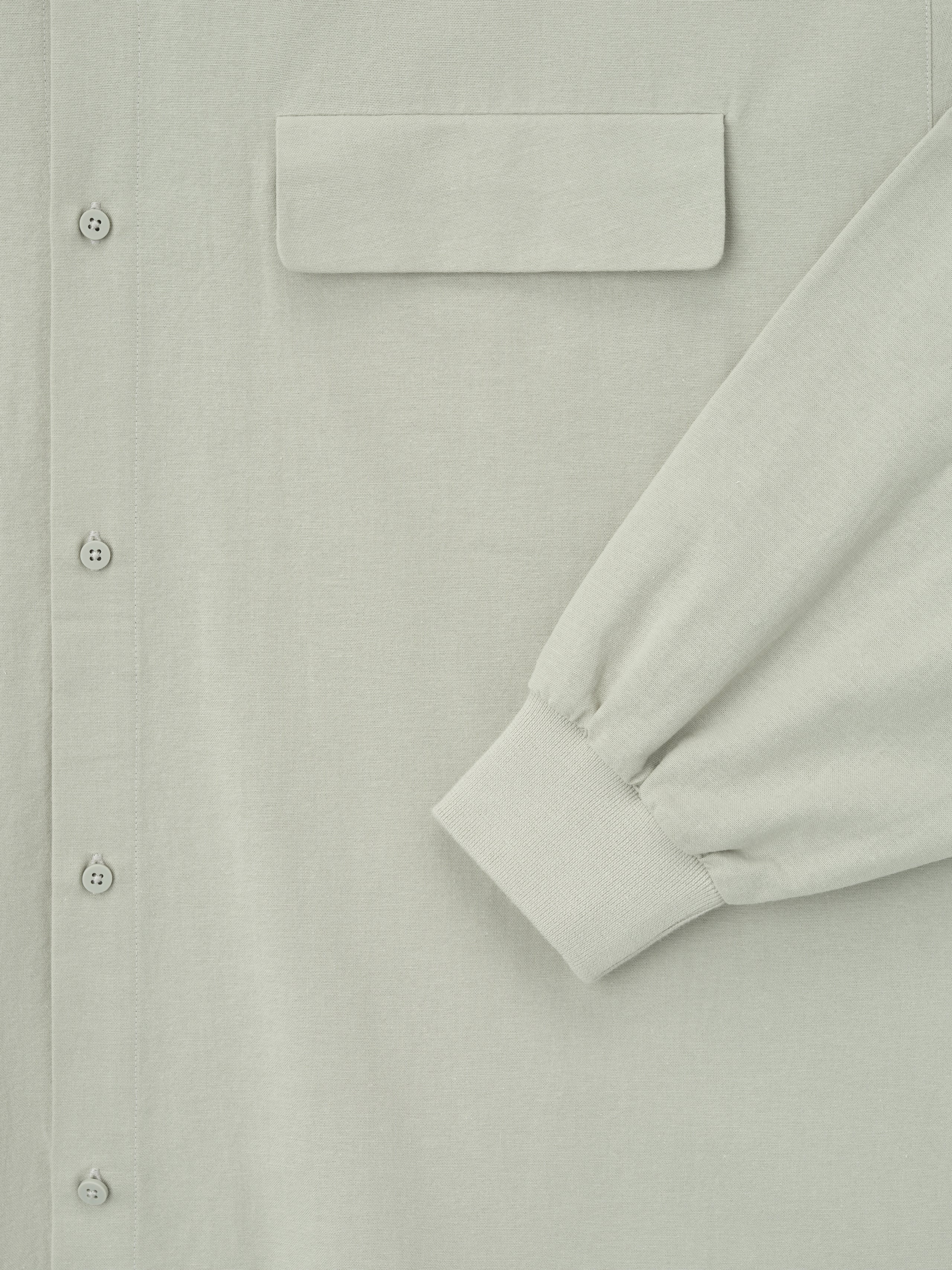 close-up of light sage oversized Oxford shirt with flap chest pocket, button front, and ribbed cuff on long sleeve detail