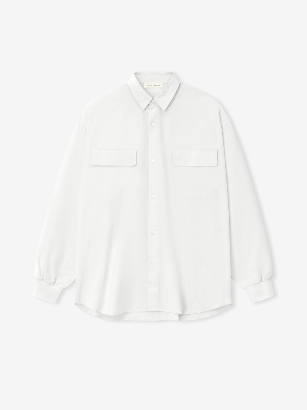 white oversized cotton Oxford shirt with long sleeves, flap chest pockets, and buttoned cuffs laid flat on white background