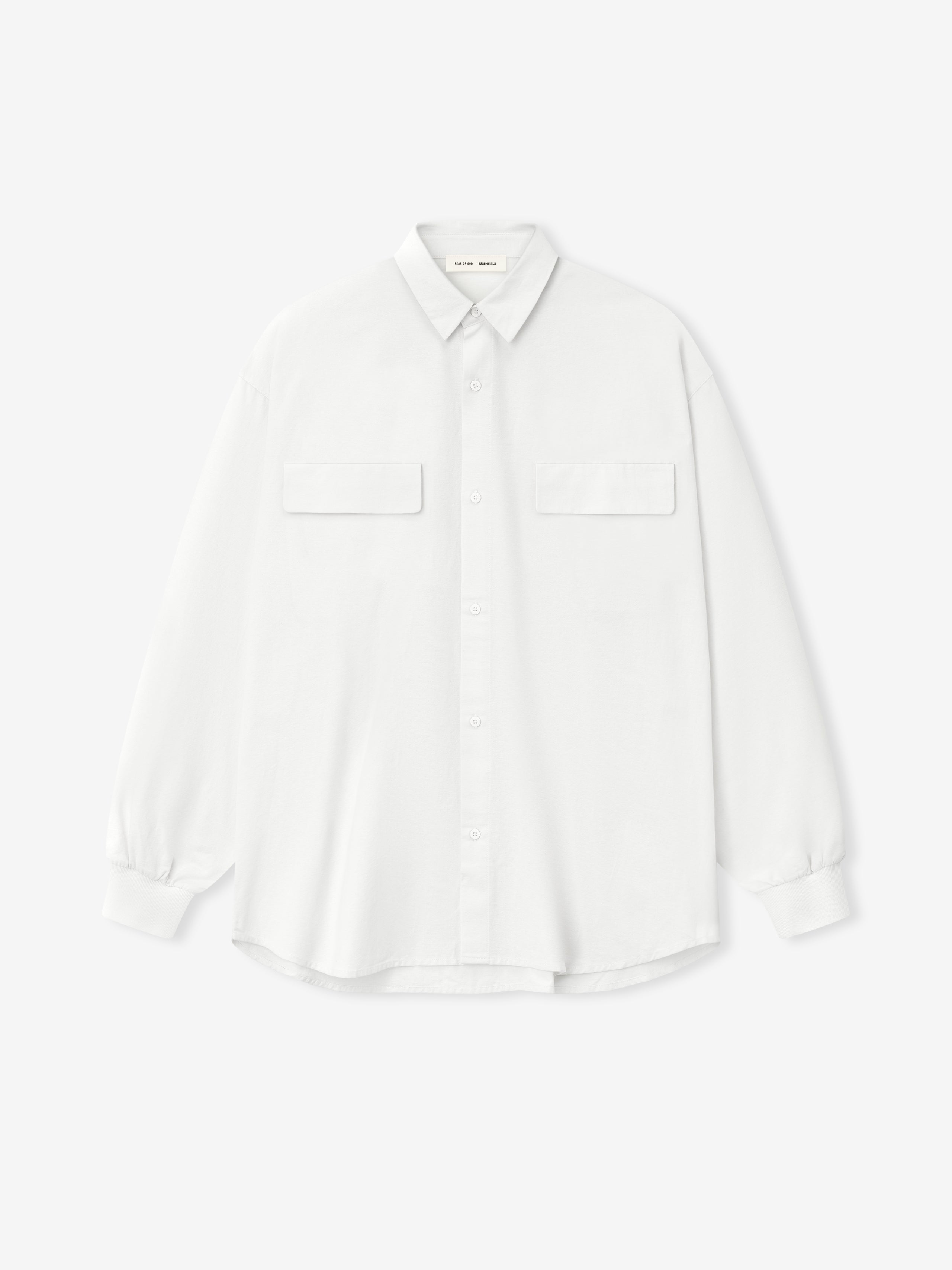 white oversized cotton Oxford shirt with long sleeves, flap chest pockets, and buttoned cuffs laid flat on white background
