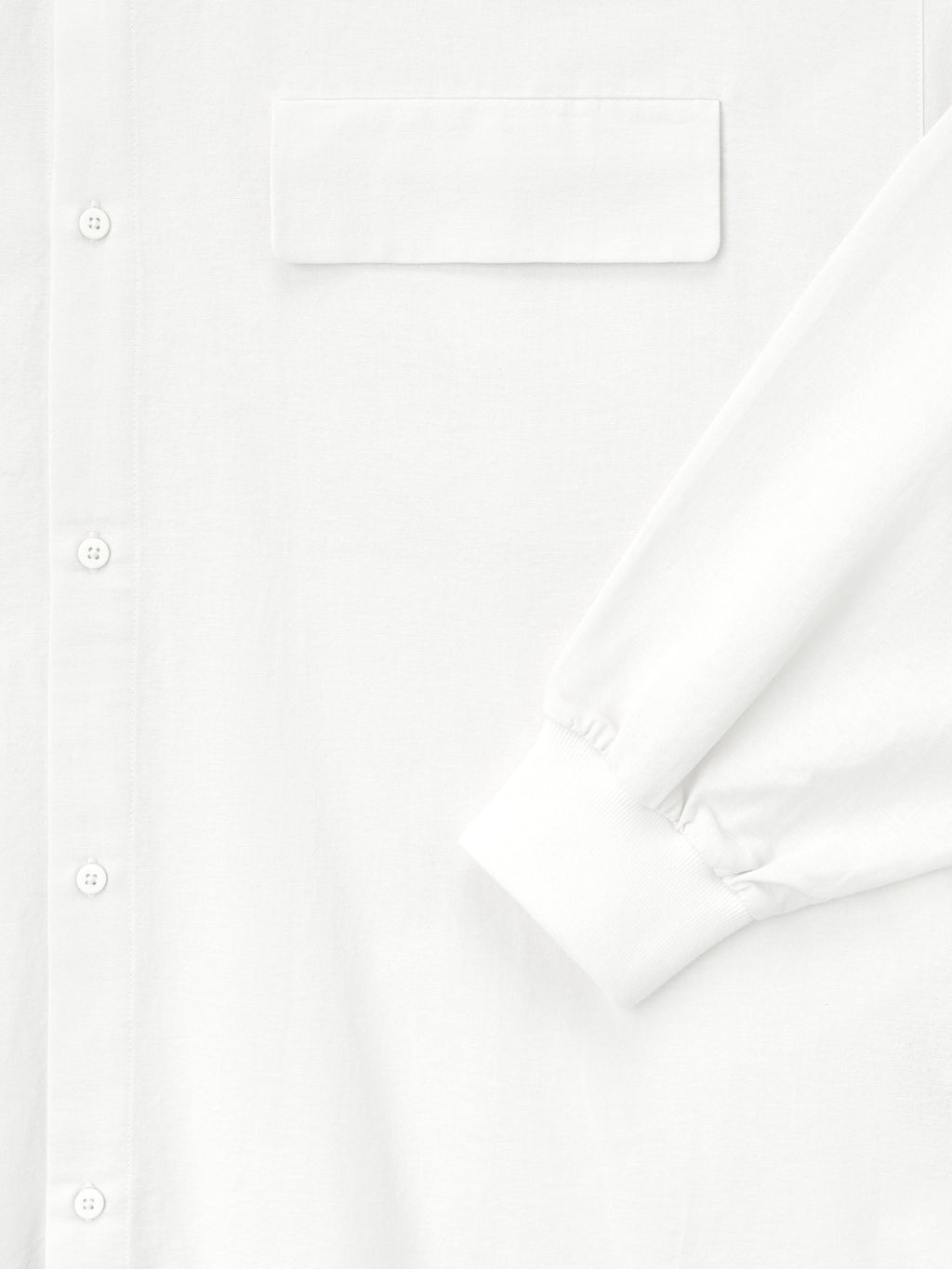 close-up of white Oxford shirt showing button placket, flap chest pocket, and elasticated cuff on long sleeve detail