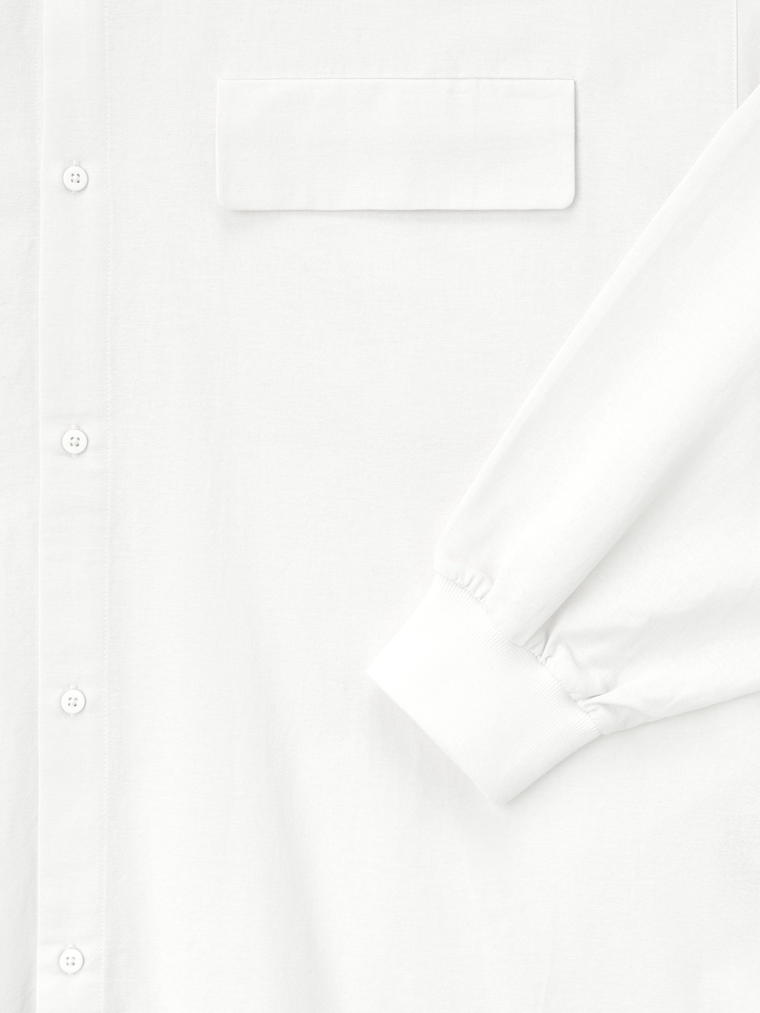 close-up of white Oxford shirt showing button placket, flap chest pocket, and elasticated cuff on long sleeve detail