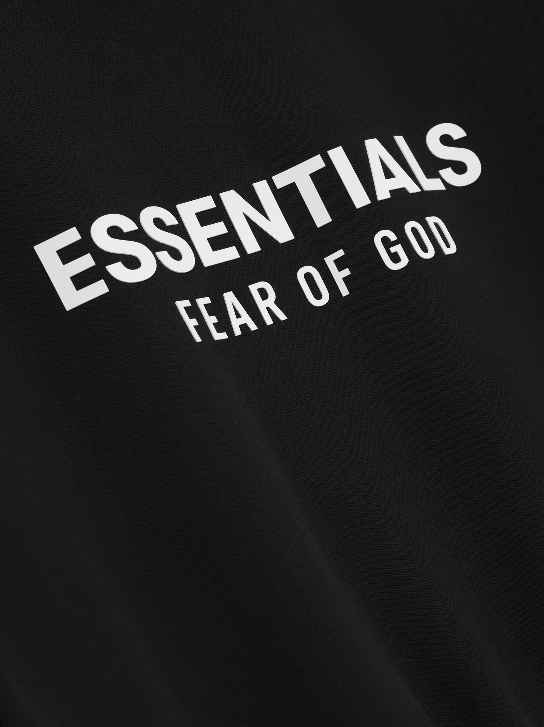 Close-up of white ESSENTIALS Fear of God logo printed on jet black Classic Crewneck Sweatshirt fabric, gallery image 0