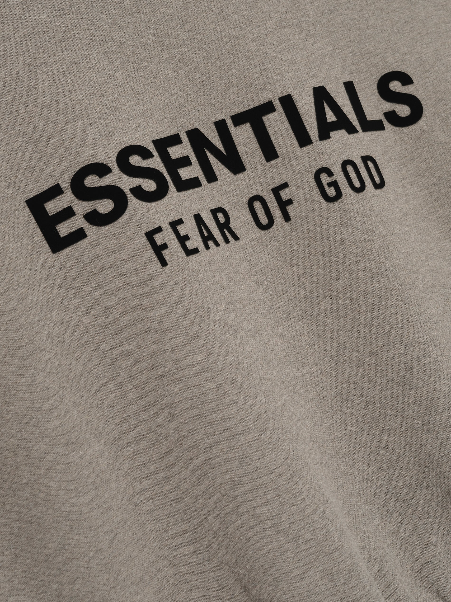 Close-up of Homestead Heather Classic Fit Fleece Hoodie fabric with black ESSENTIALS Fear of God logo, gallery image 0.