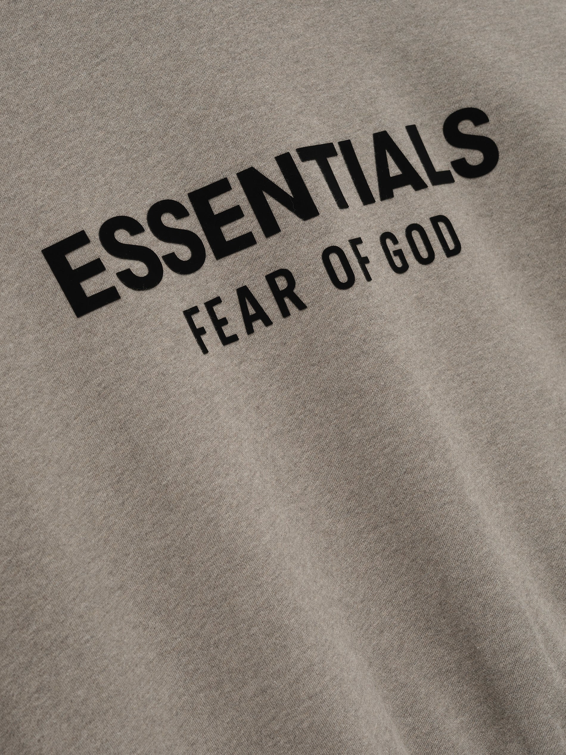 Close-up of Homestead Heather fleece fabric showing black Essentials Fear of God logo print on Classic Full Zip Up Hoodie