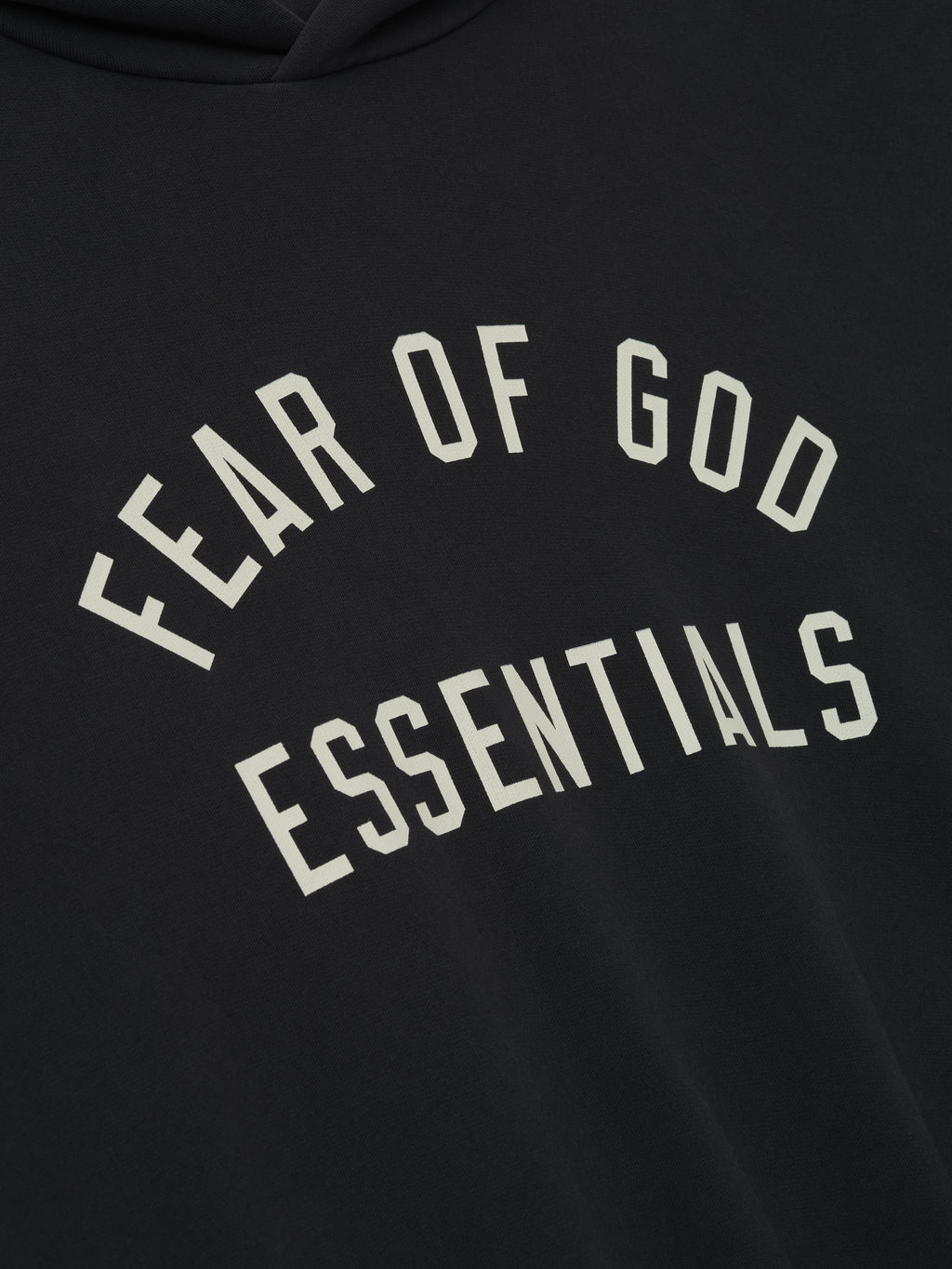 Close-up of black 90s Fit Hoodie fabric with bold Fear of God Essentials logo printed in off-white letters