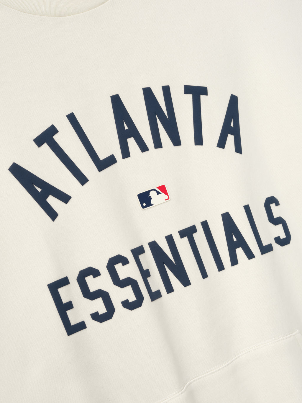 Off-white fabric close-up featuring navy blue "ATLANTA ESSENTIALS" text with small MLB logo centered between words