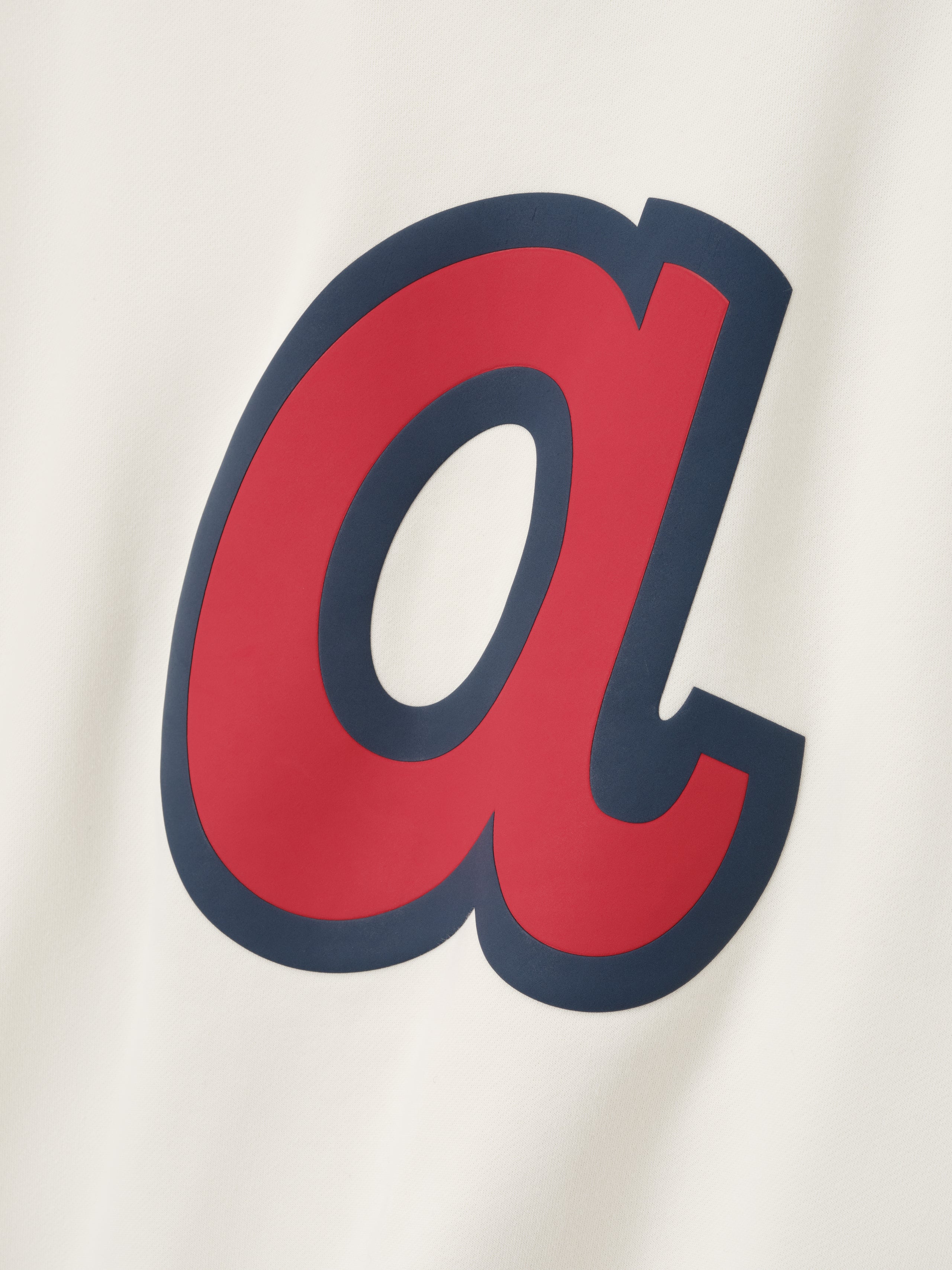 Close-up of cream-colored fabric featuring large red lowercase "a" with navy blue outline on Braves Sport crewneck