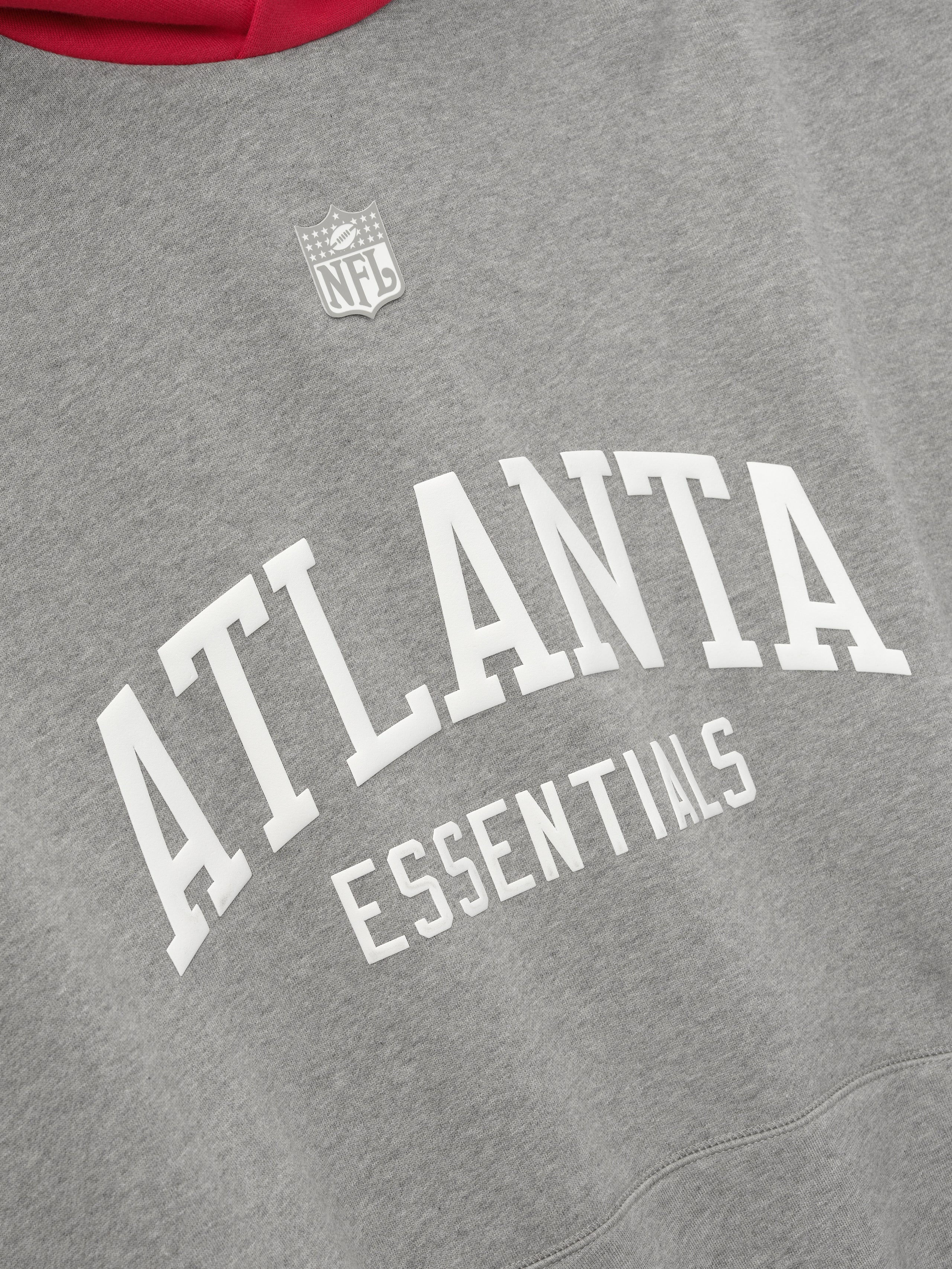 Heather grey hoodie fabric with white arched "ATLANTA ESSENTIALS" text and small NFL shield logo above on front panel