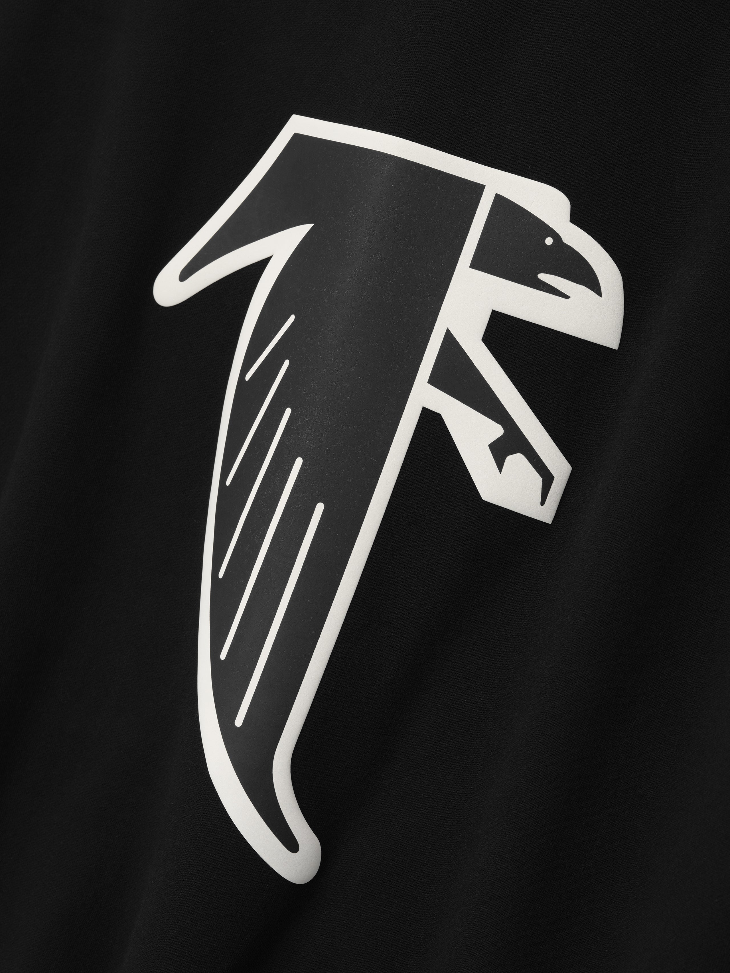 Close-up of black crewneck showing stylized white falcon graphic with bold outlines on fabric