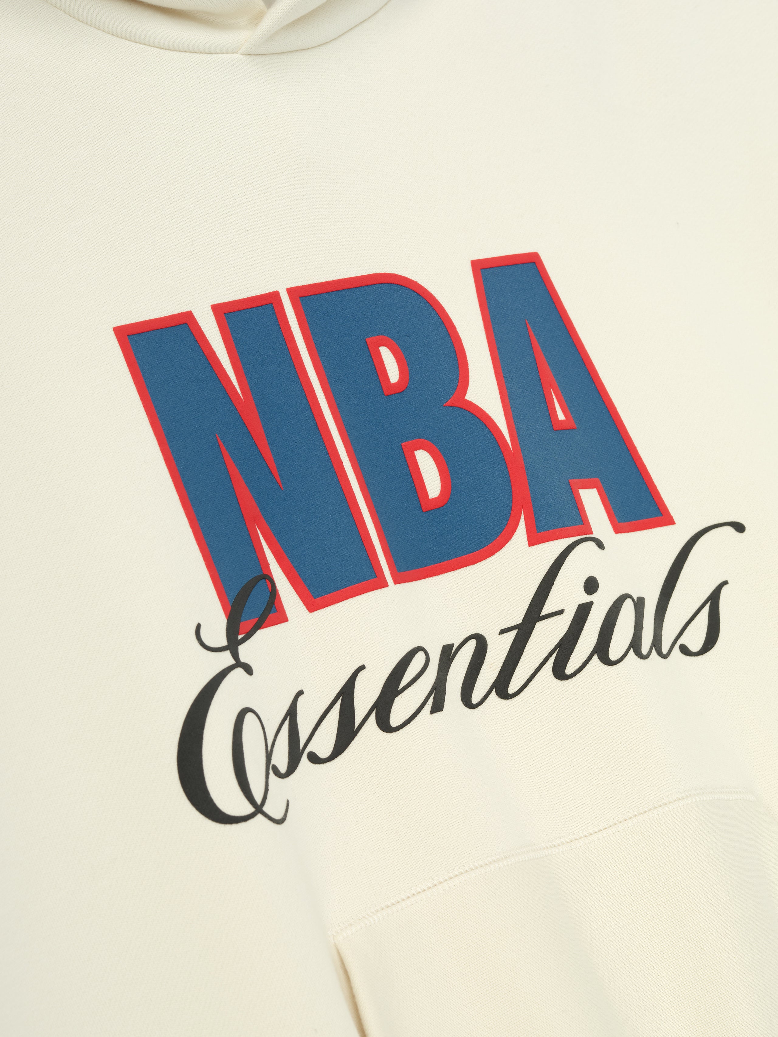 Cream white NBA 90s Hoodie close-up showing bold blue and red NBA text with black Essentials script above kangaroo pocket