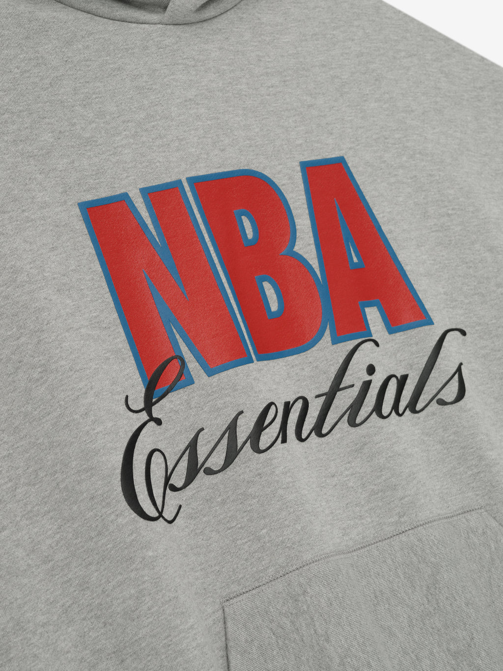 Close-up of concrete heather NBA 90s hoodie front showing bold red and blue NBA text with black "Essentials" script above kangaroo pocket