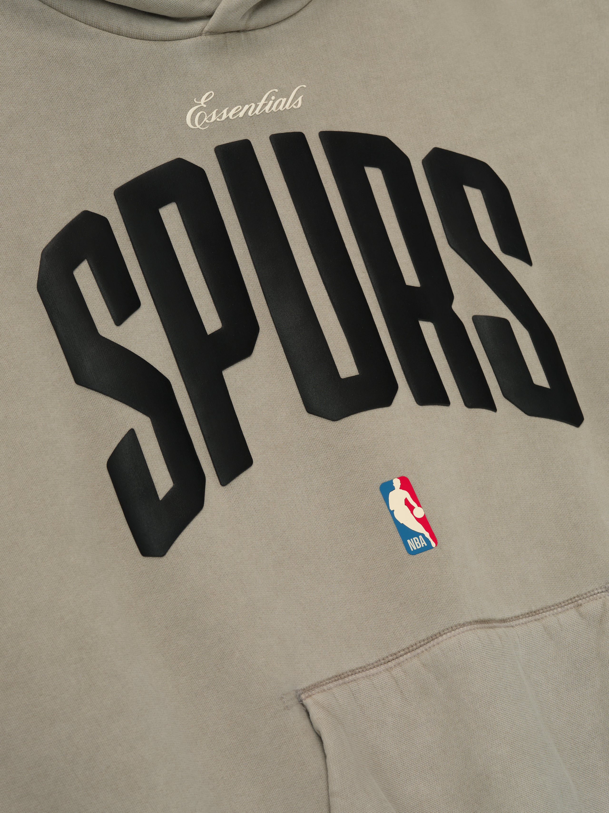 Close-up of beige Spurs 90s Hoodie front showing black arched team lettering and small NBA logo above kangaroo pocket, gallery image 0
