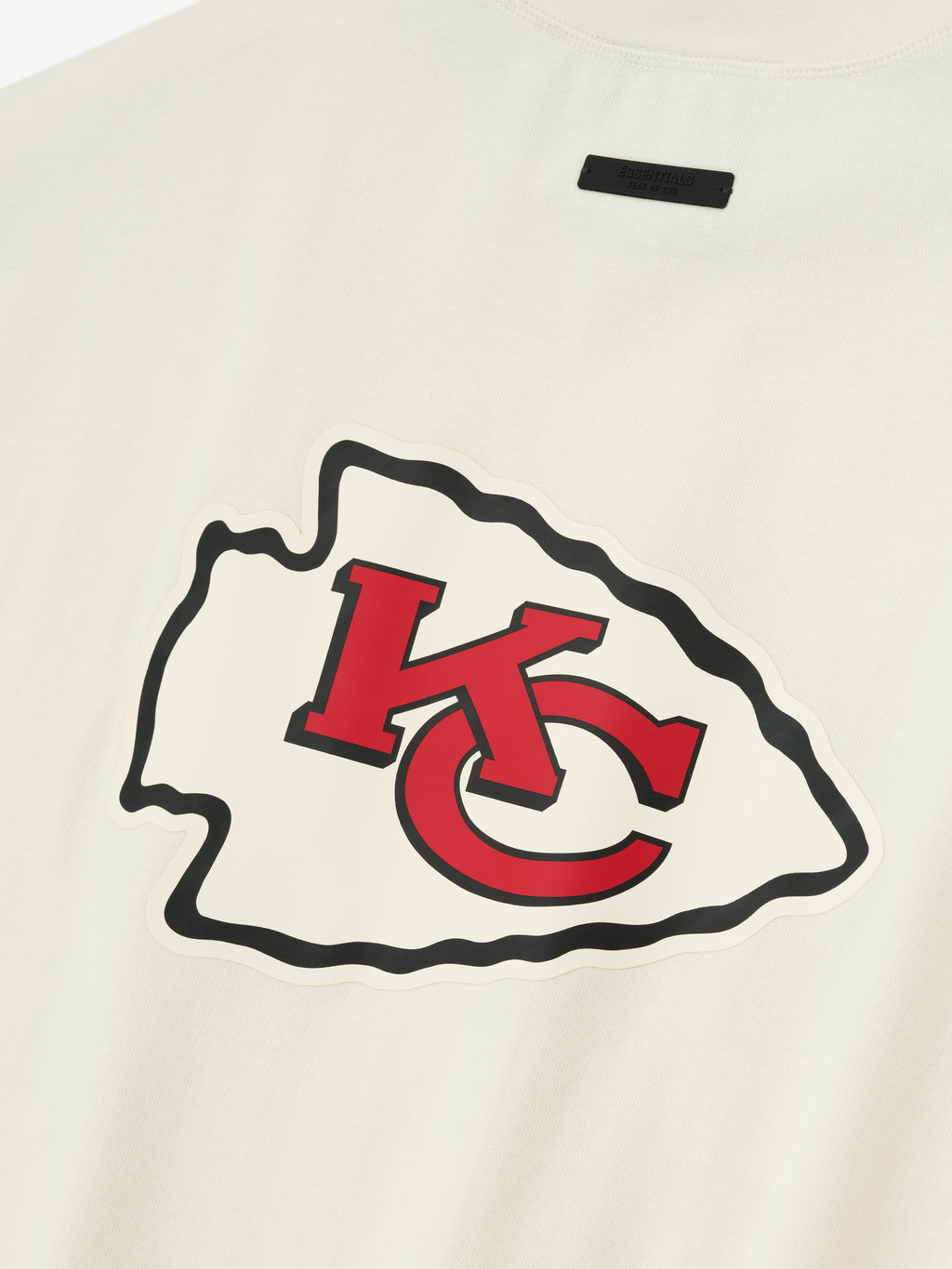 Close-up of cream white Chiefs 90s 3/4 Sleeve Football Tee featuring large red and black KC arrowhead logo on chest