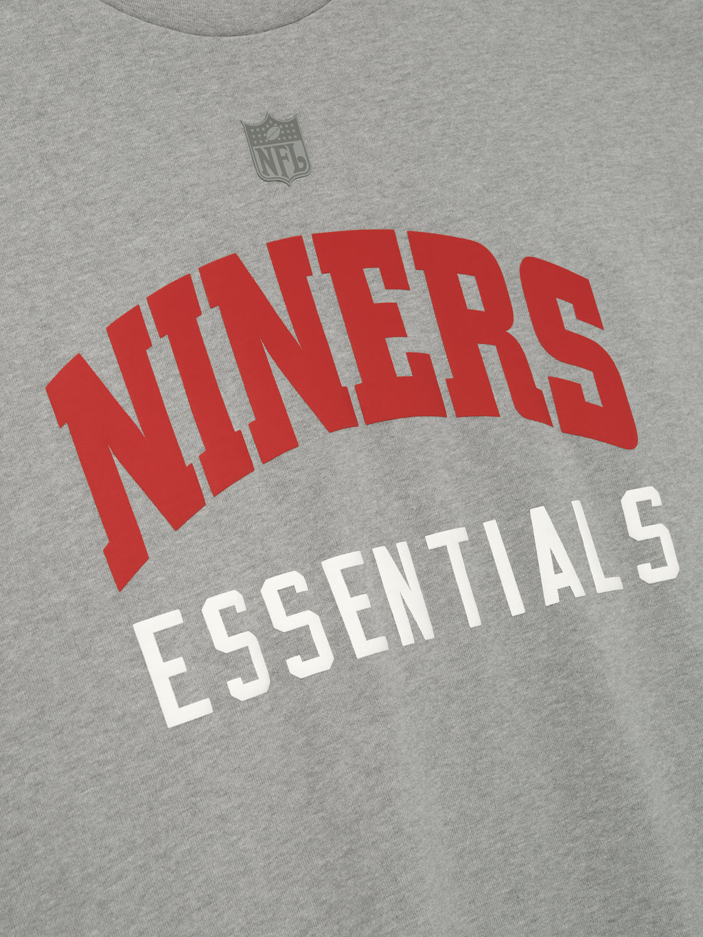 Close-up of concrete heather Forty Niners 90s 3/4 Sleeve Football Tee showing bold red NINERS and white Essentials text