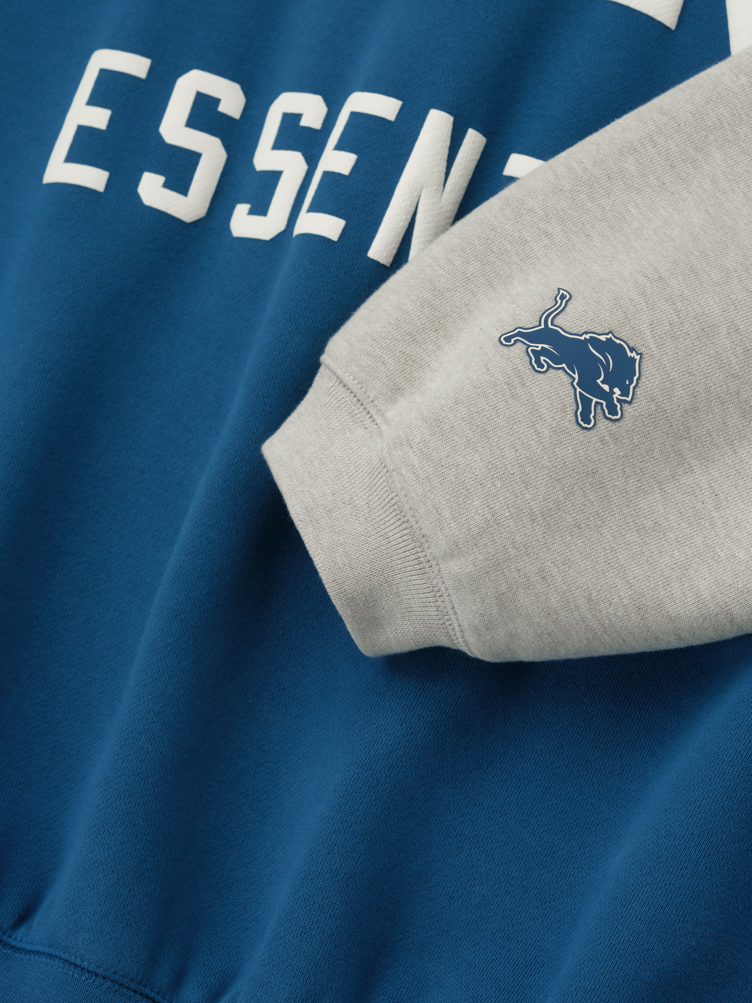 Close-up of Lions Sport Hoodie in blue sapphire with heather stone sleeve and small blue Lions logo patch on cuff