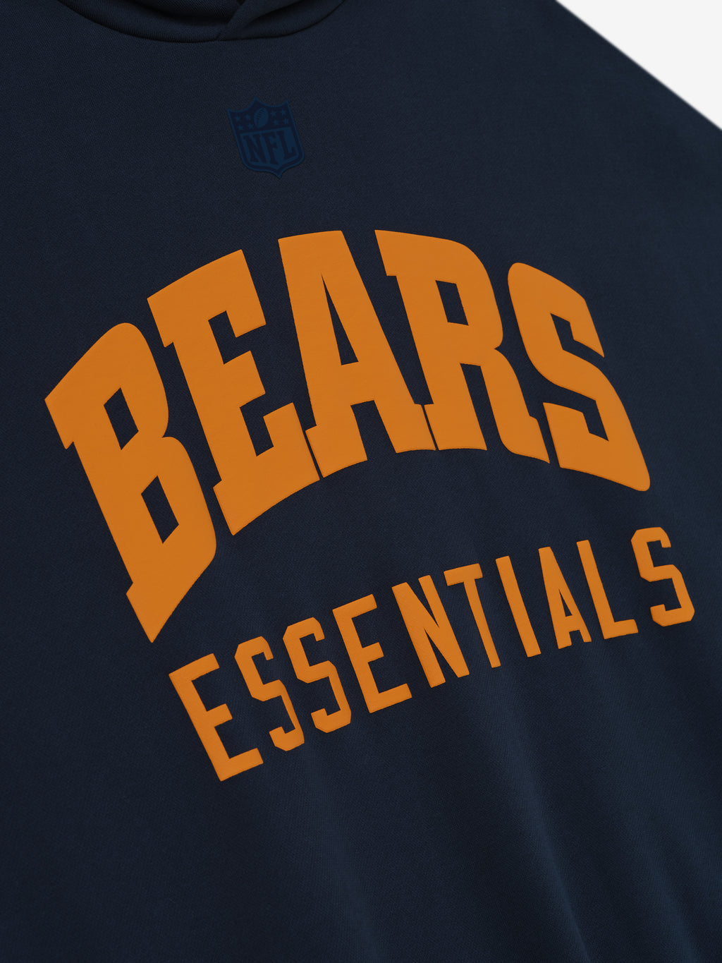 Close-up of dark sapphire Bears Sport Hoodie showing bold orange BEARS and ESSENTIALS text with subtle black NFL shield above
