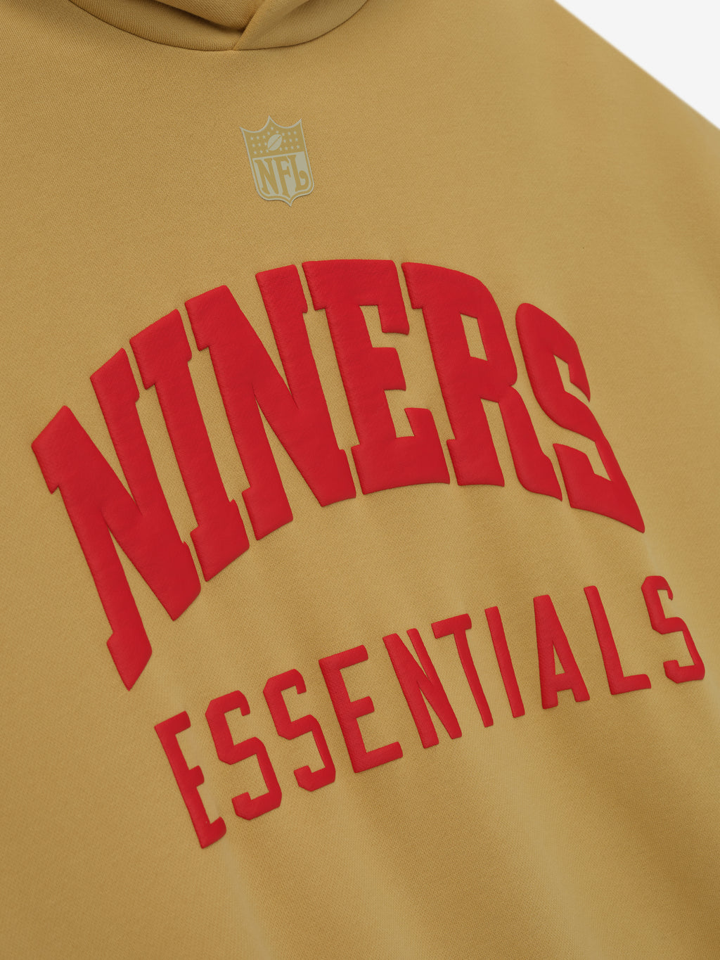 Close-up of Forty Niners Sport Hoodie in prairie sand showing raised red Niners and Essentials text with silver NFL logo above