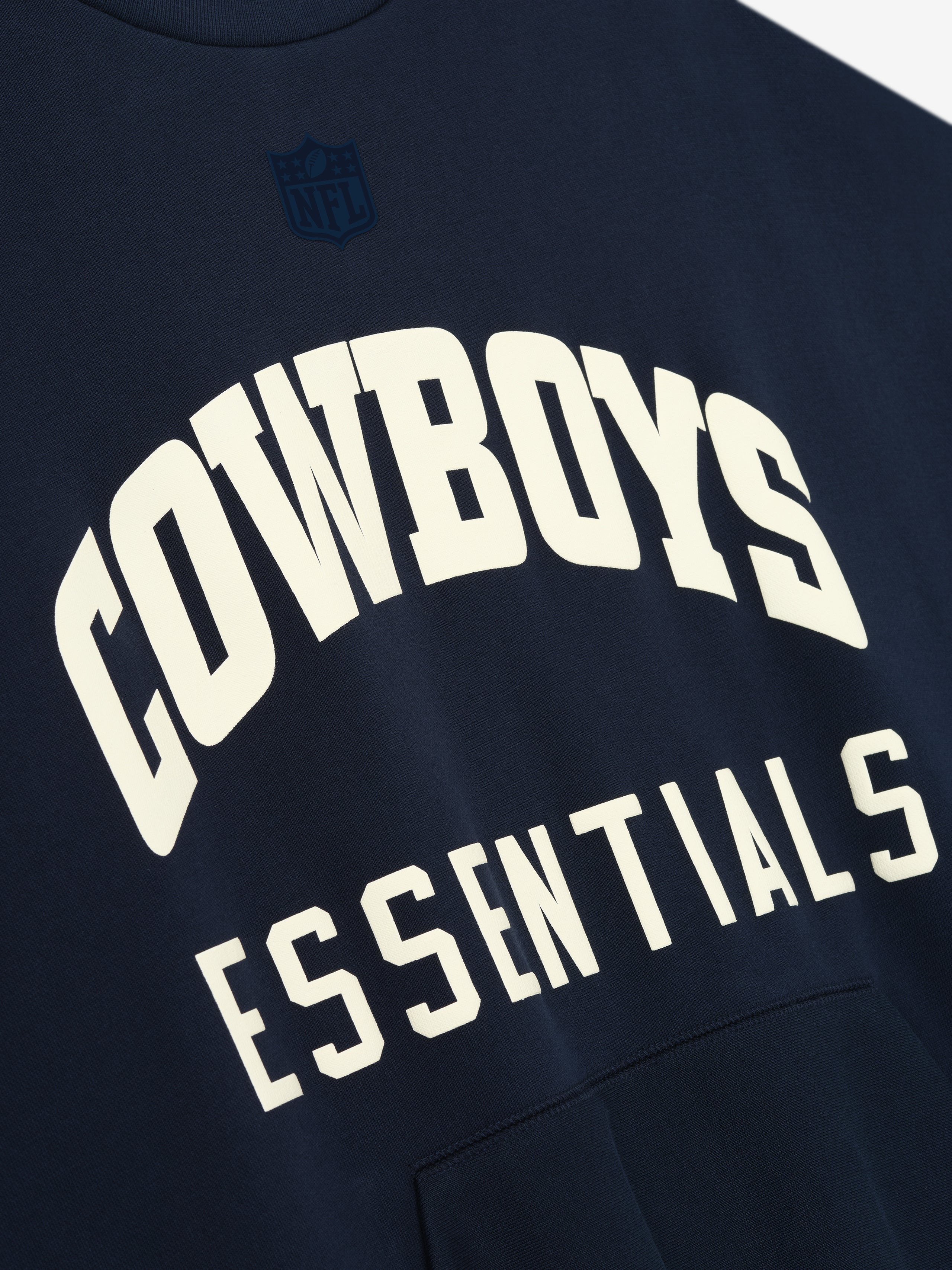 Dark sapphire fabric with large cream "COWBOYS" arch text above block "ESSENTIALS" lettering and front kangaroo pocket