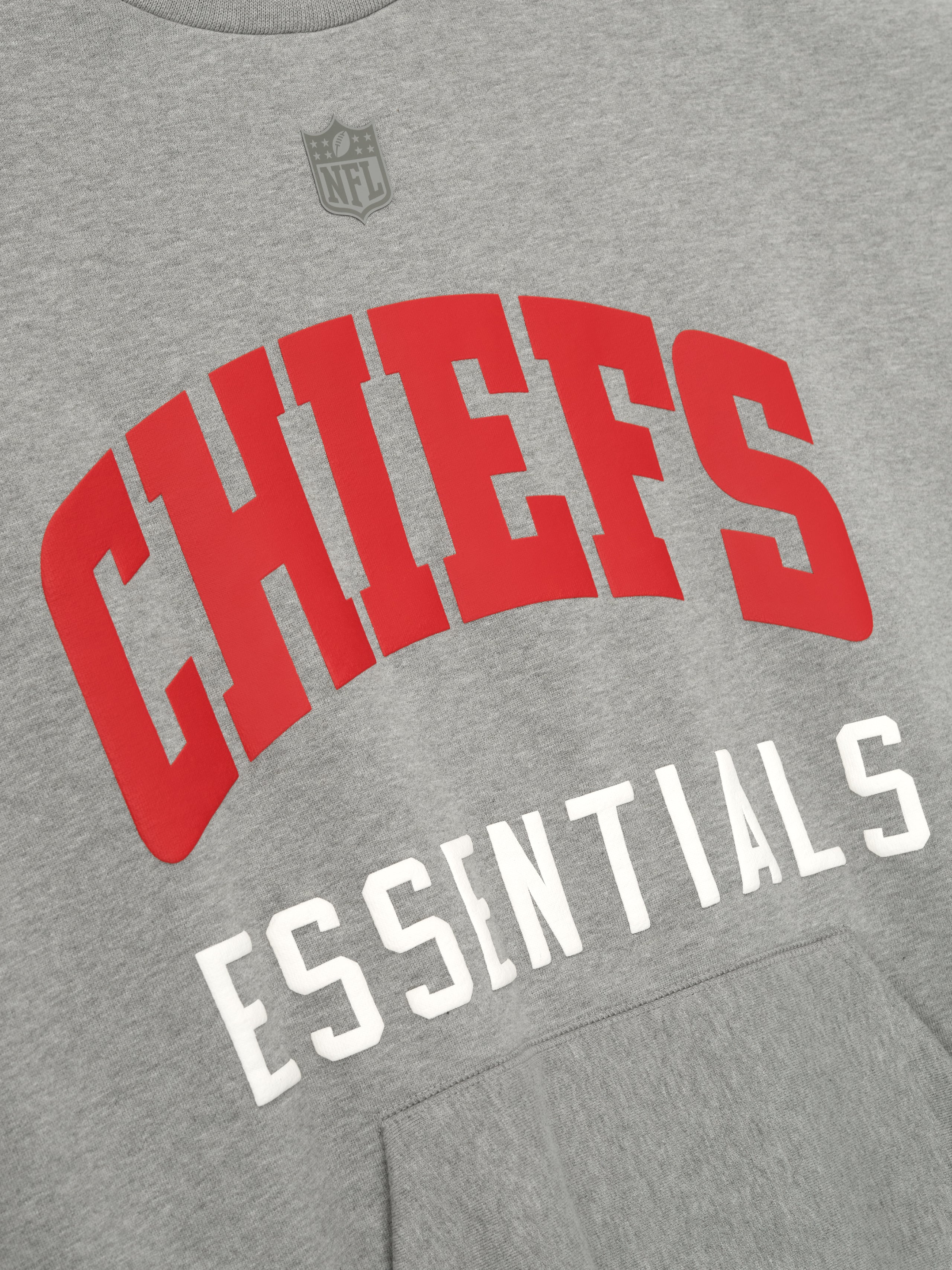 Detailed close-up of concrete heather Chiefs Sport Crewneck showing large red Chiefs text and white Essentials below chest, gallery 0