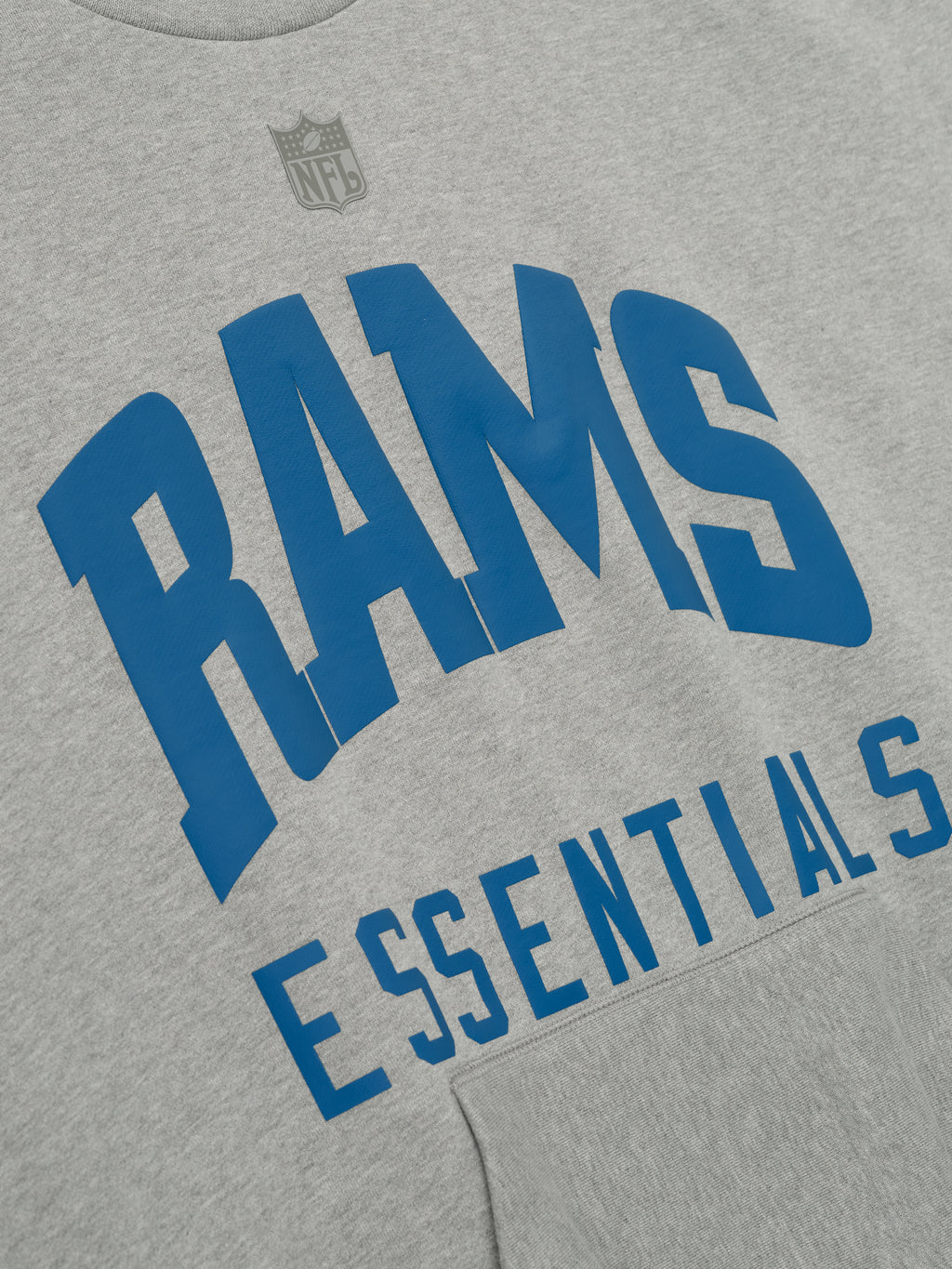 Close-up of concrete heather Rams Sport Crewneck showing bold blue Rams Essentials text with subtle NFL shield above chest, gallery 0