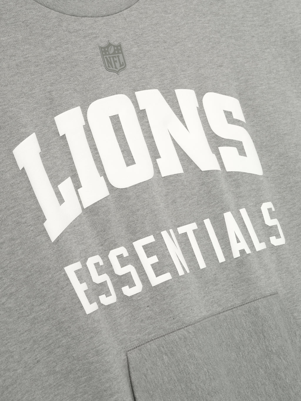 Close-up of concrete heather Lions Sport Crewneck showing bold white Lions Essentials text and subtle NFL shield above chest, gallery 0