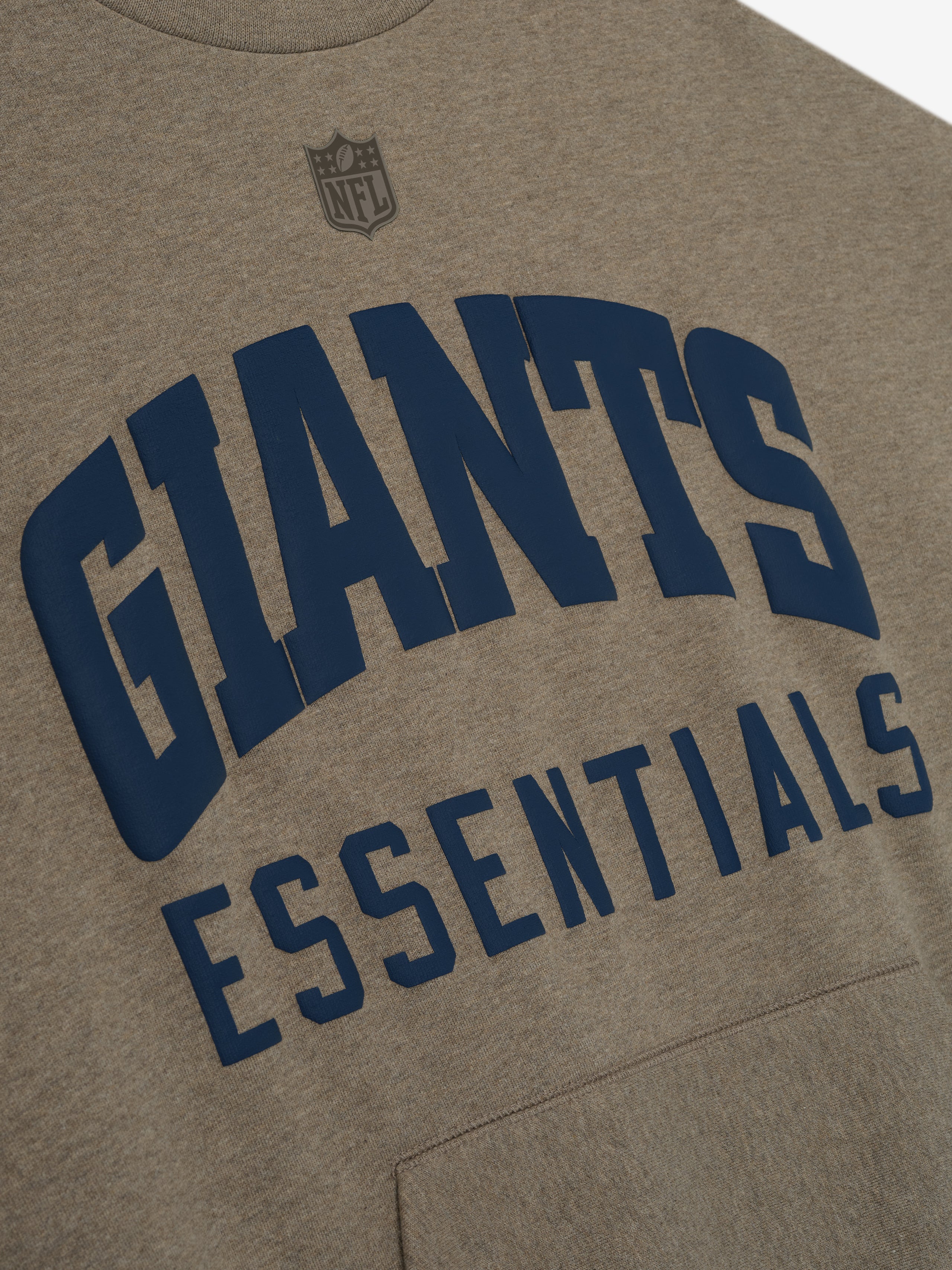 Close-up of homestead heather Giants Sport Crewneck showing navy Giants Essentials lettering with small NFL shield above chest