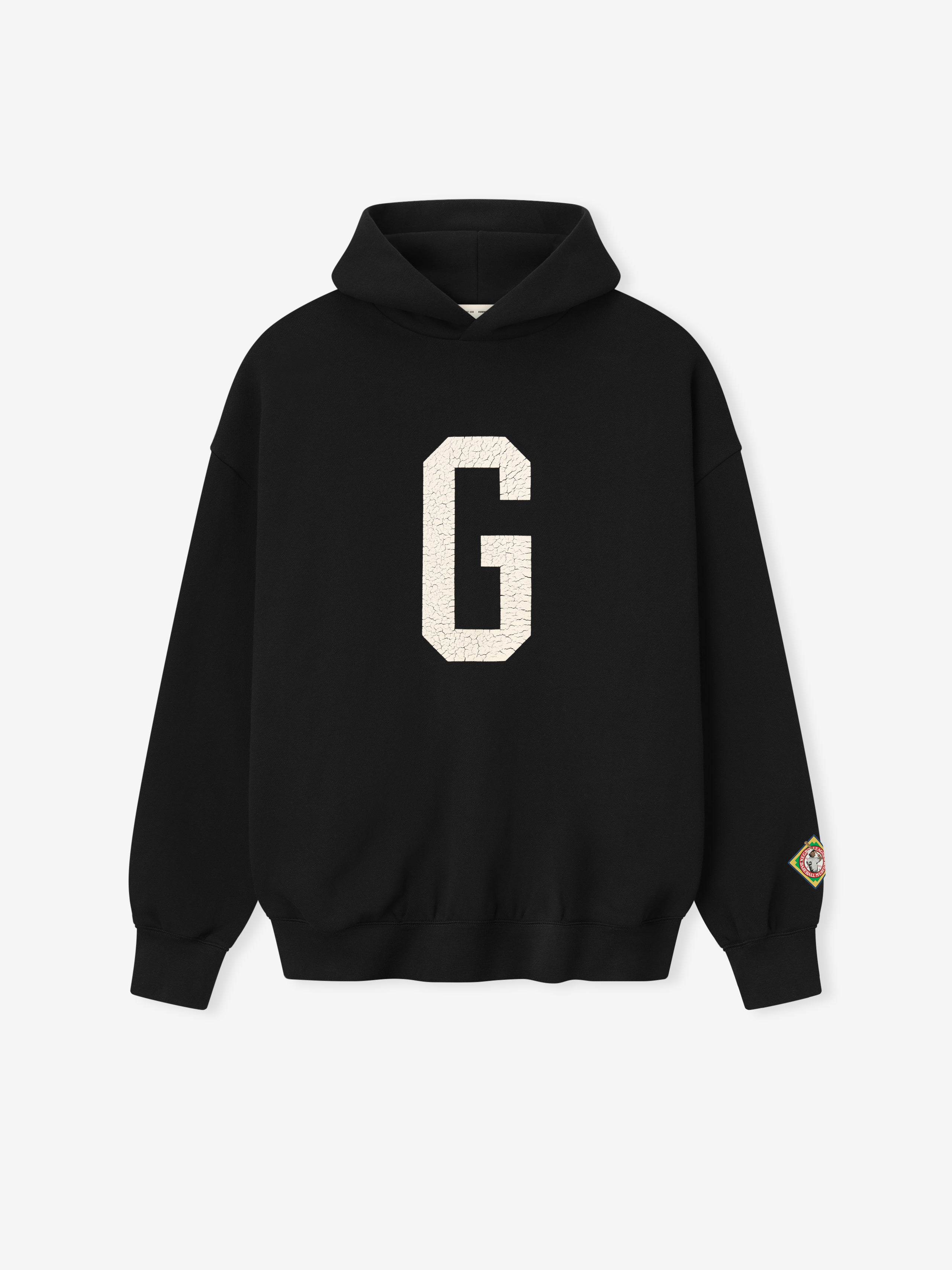 black Essentials hoodie with large white felt "G" graphic on front and colorful patch on left sleeve cuff