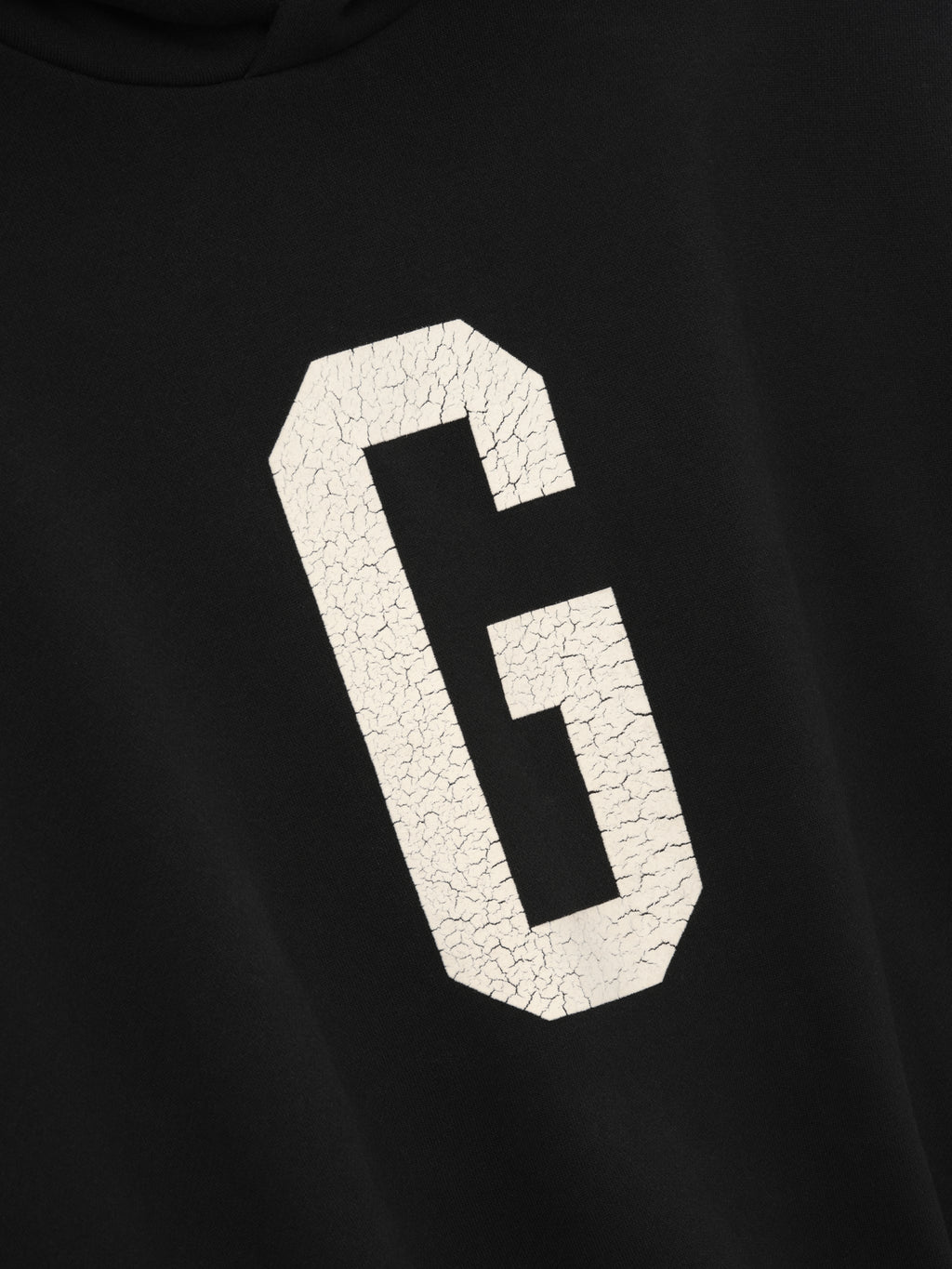 close-up of black hoodie front with large cracked white felt "G" graphic from Essentials Grays collection