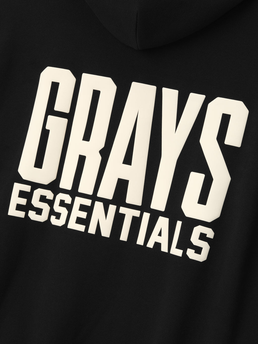 black hoodie back with bold cream "GRAYS ESSENTIALS" text printed in large block letters