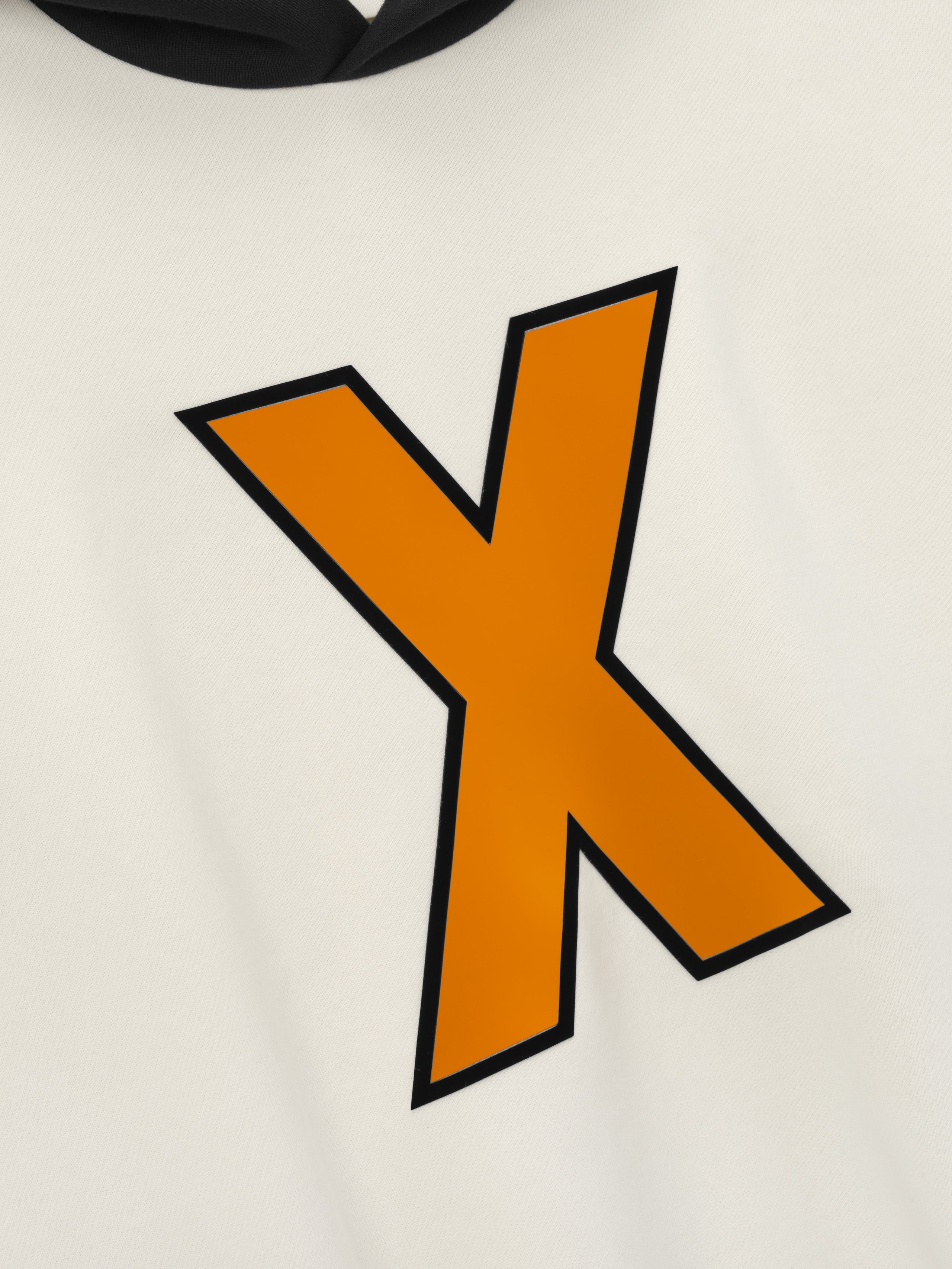 close-up of cream hoodie front featuring a bold orange "X" graphic with black outline and black hood detail visible above