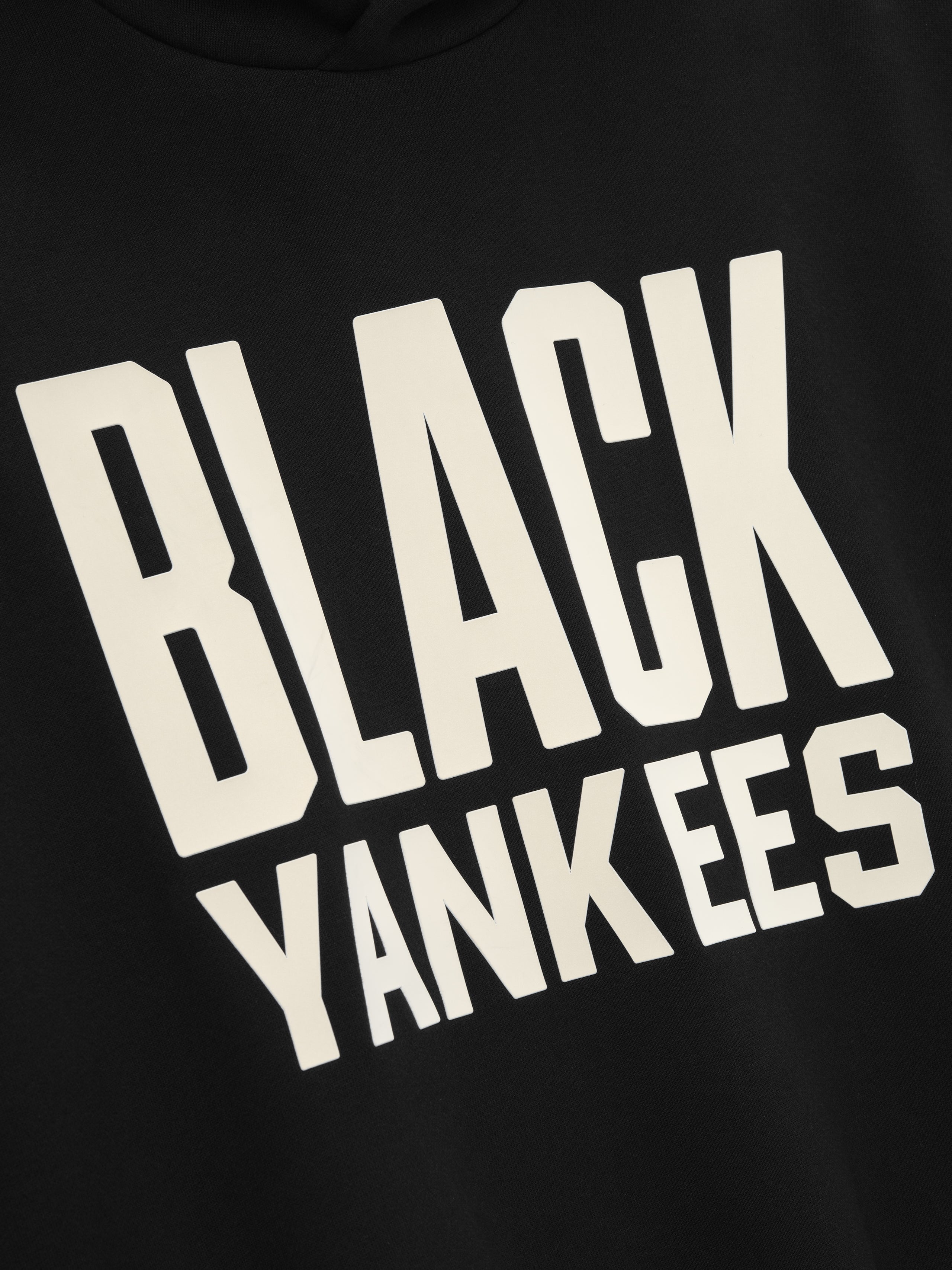 close-up of black hoodie front with large cream "BLACK YANKEES" text in bold block lettering