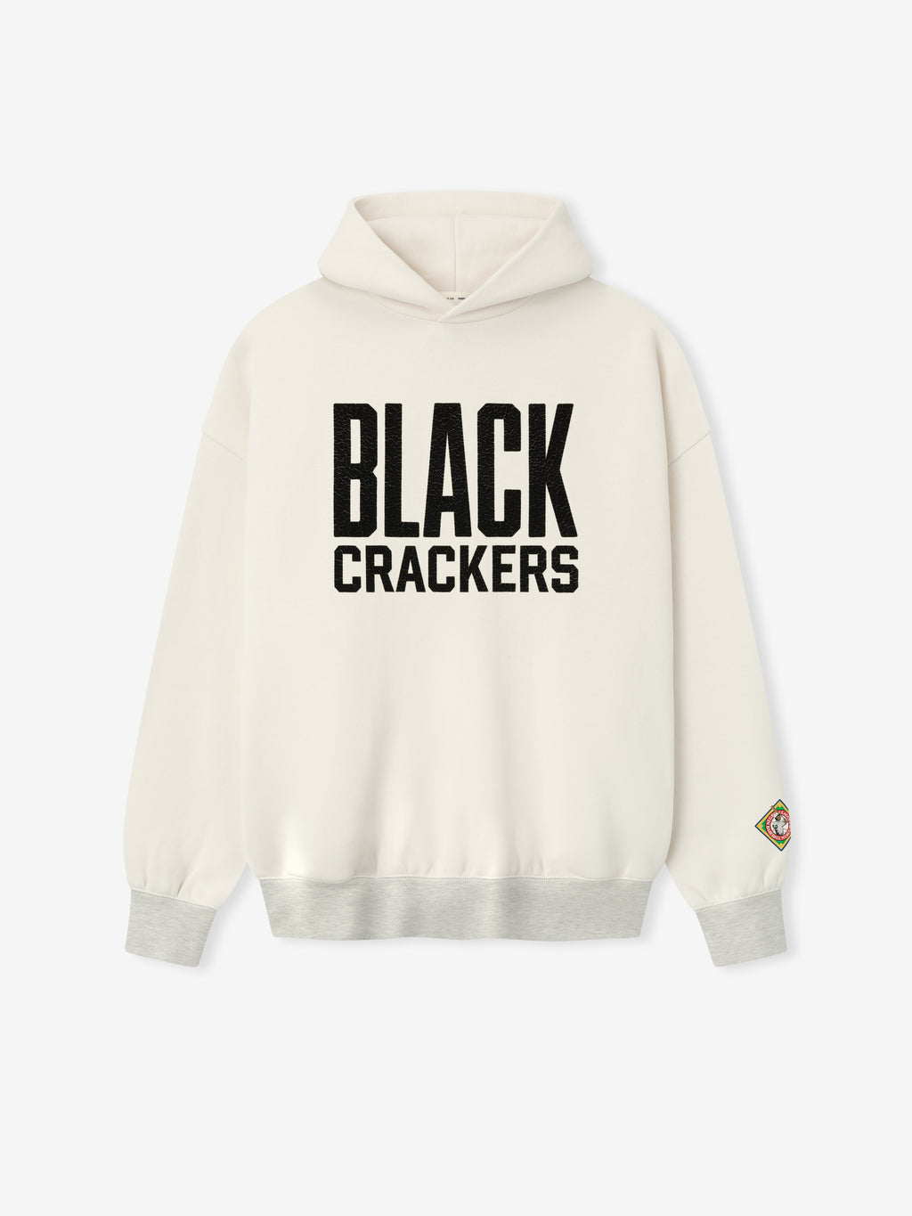 cream hoodie featuring bold black "BLACK CRACKERS" felt graphic on front and multicolored patch on left sleeve cuff