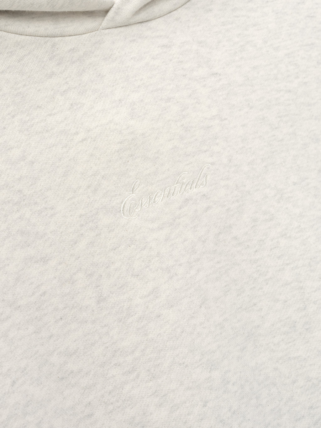 Close-up of a light gray textured fabric with essentials embroidery 