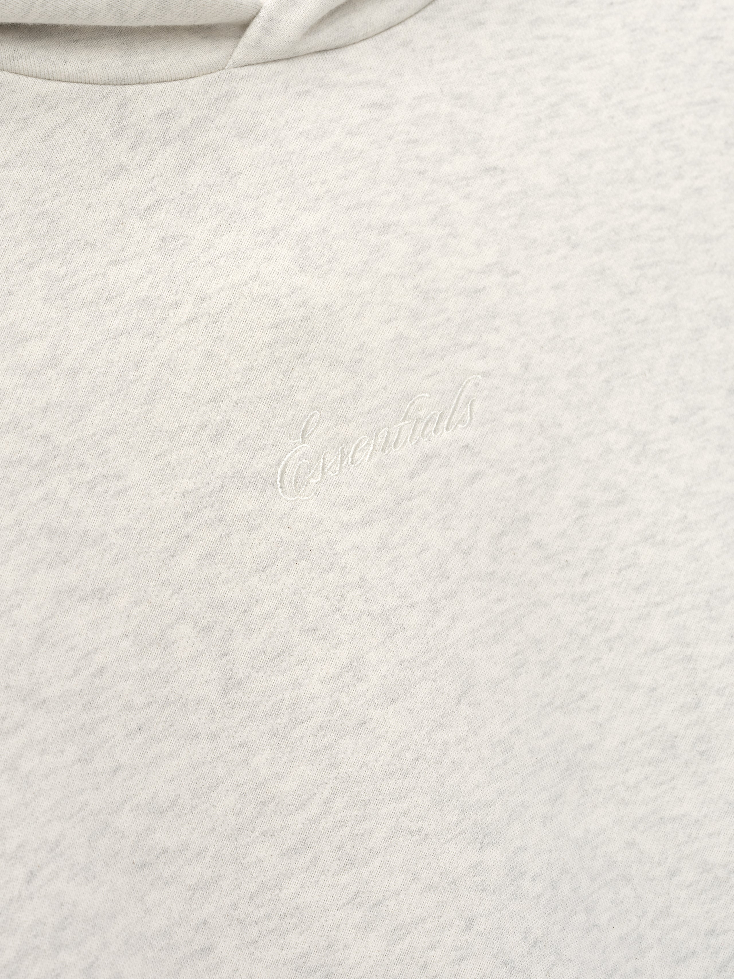 Close-up of a light gray textured fabric with essentials embroidery 