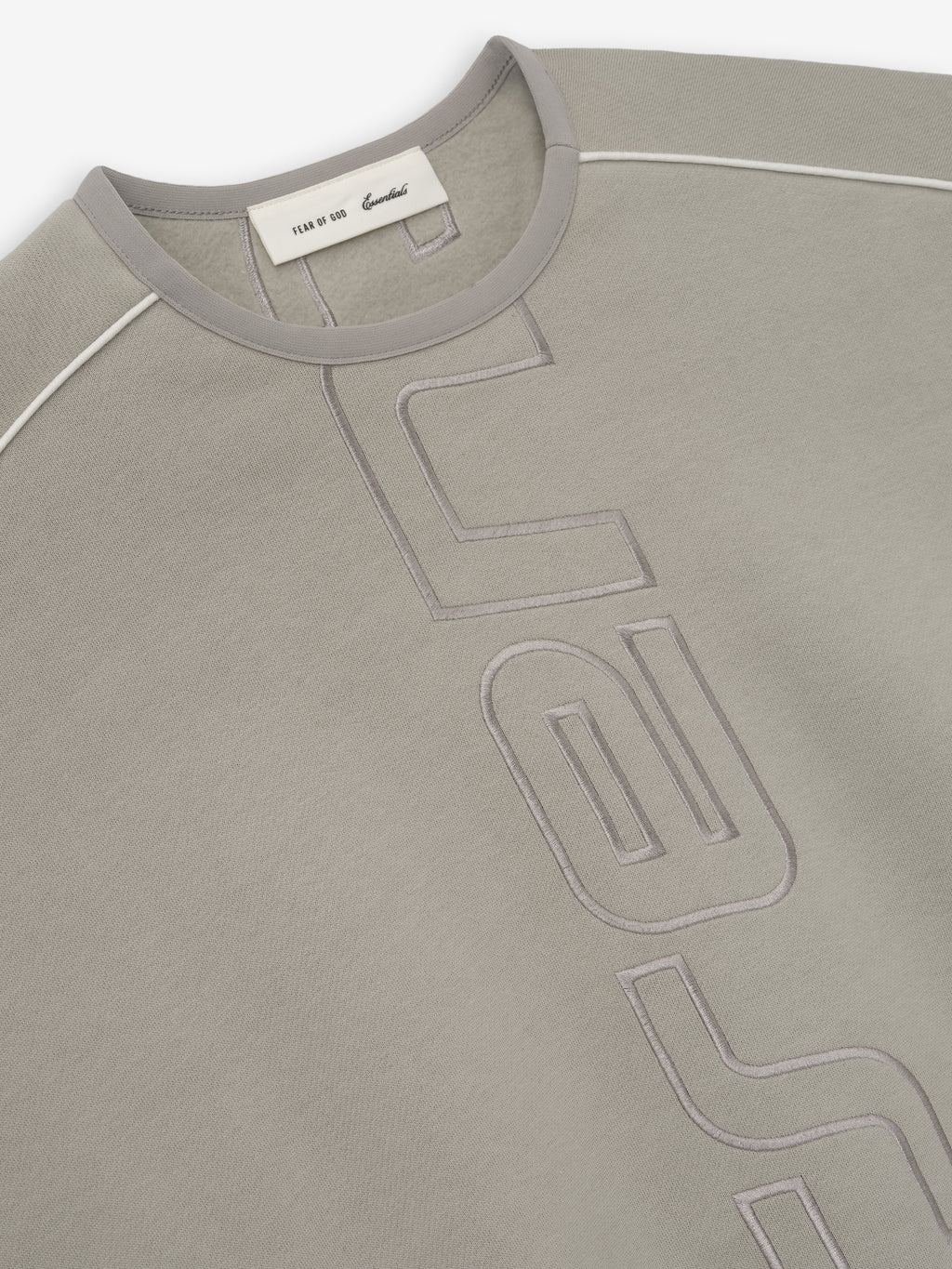 Close-up of taupe sweatshirt front with tonal raised graphic lettering and contrasting stitching on shoulder seams