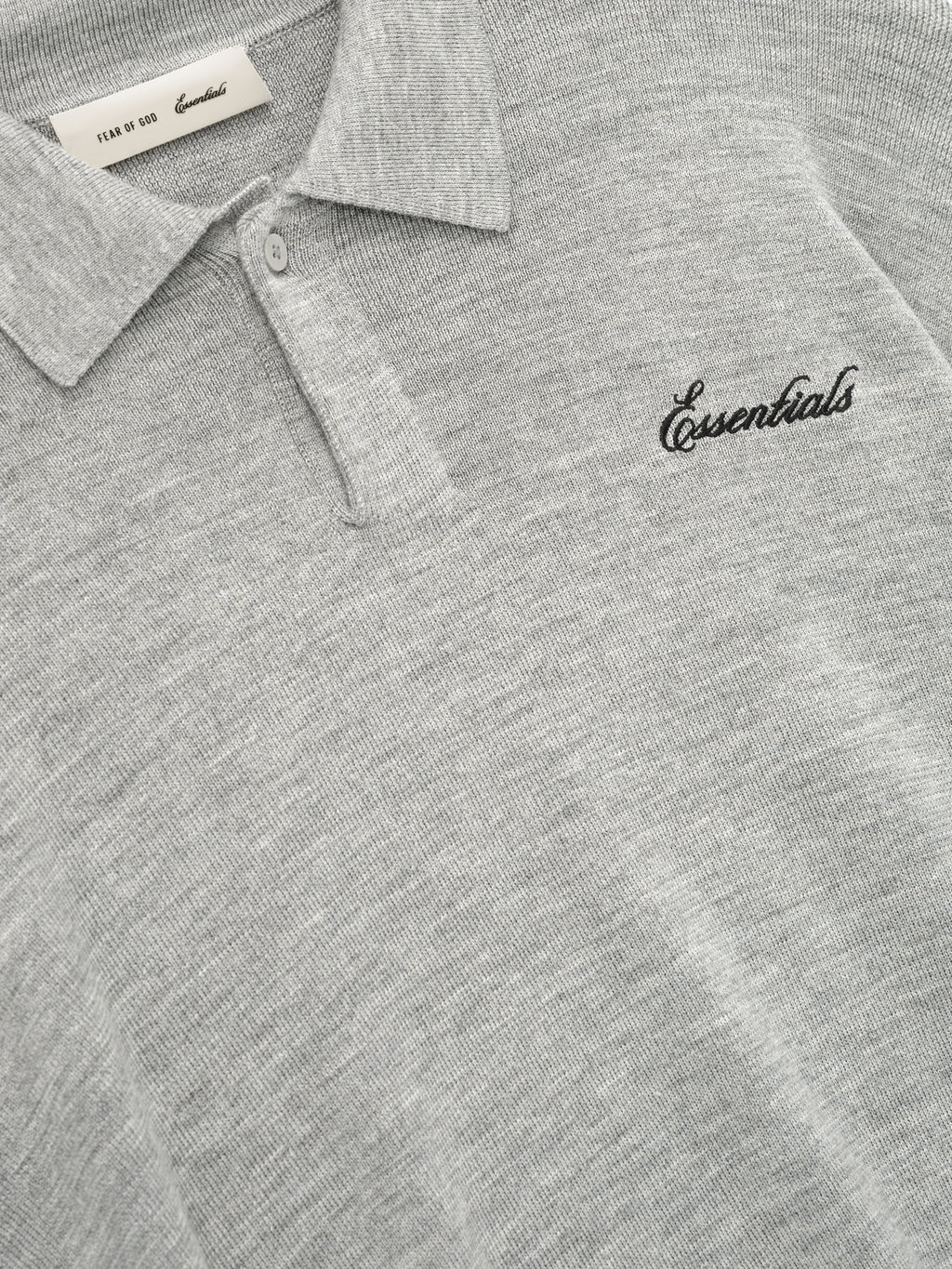 Gray polo shirt with 'Essentials' logo on a close-up view