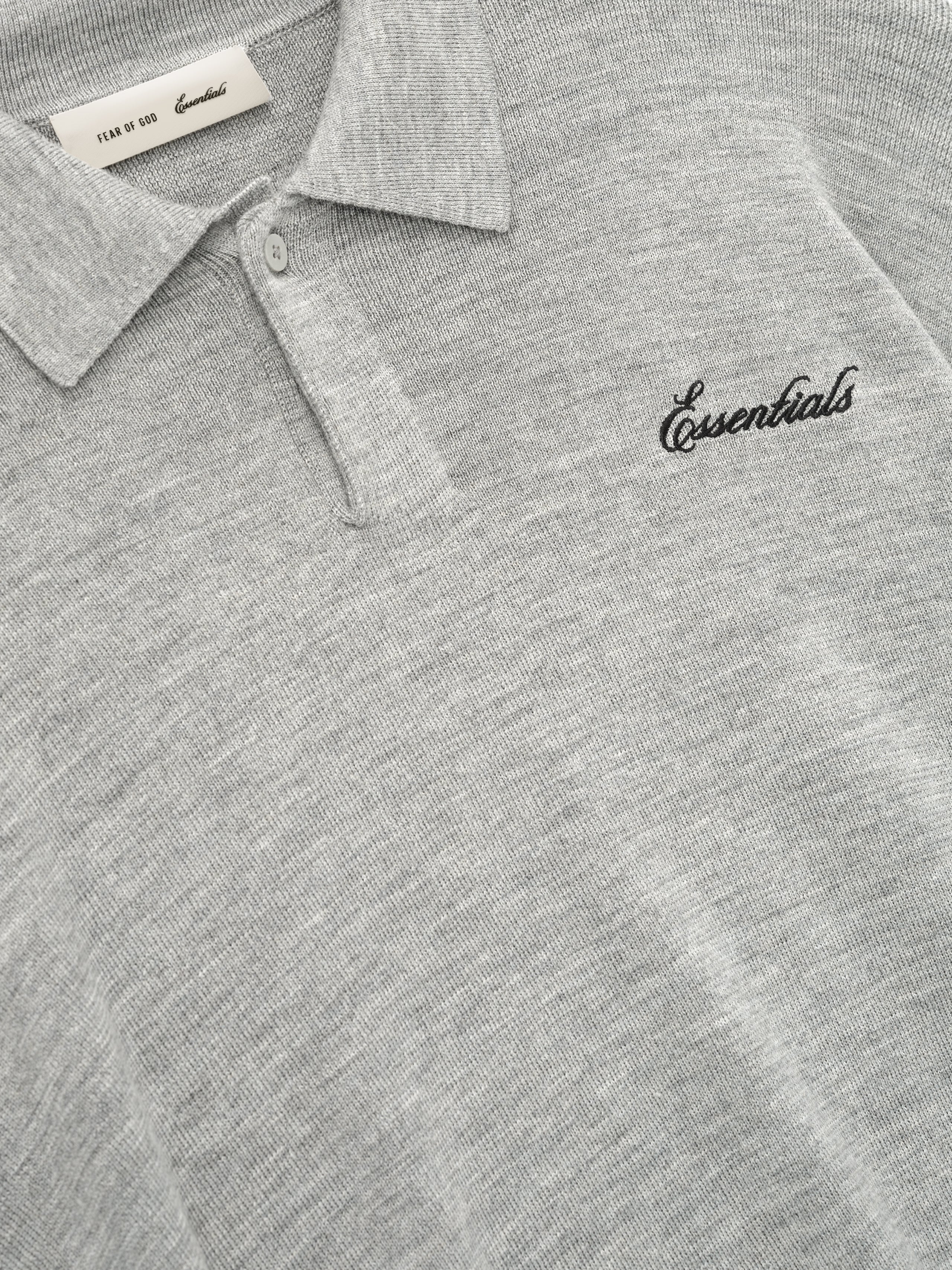 Gray polo shirt with 'Essentials' logo on a close-up view