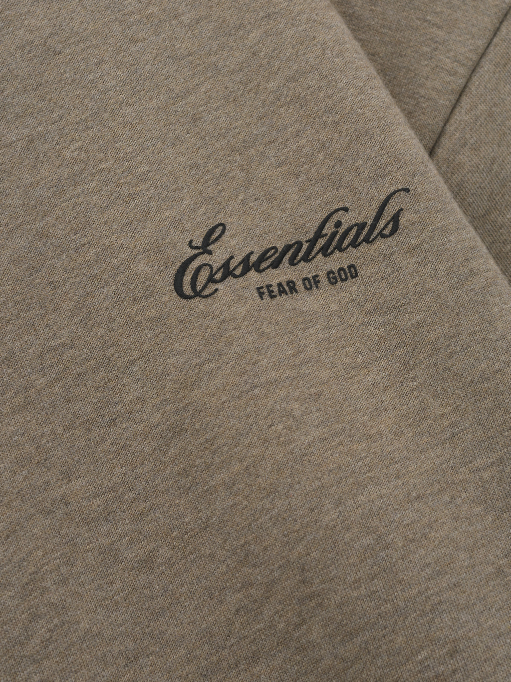 close-up of taupe core fleece fabric with Essentials Fear of God scripted logo printed on front chest panel