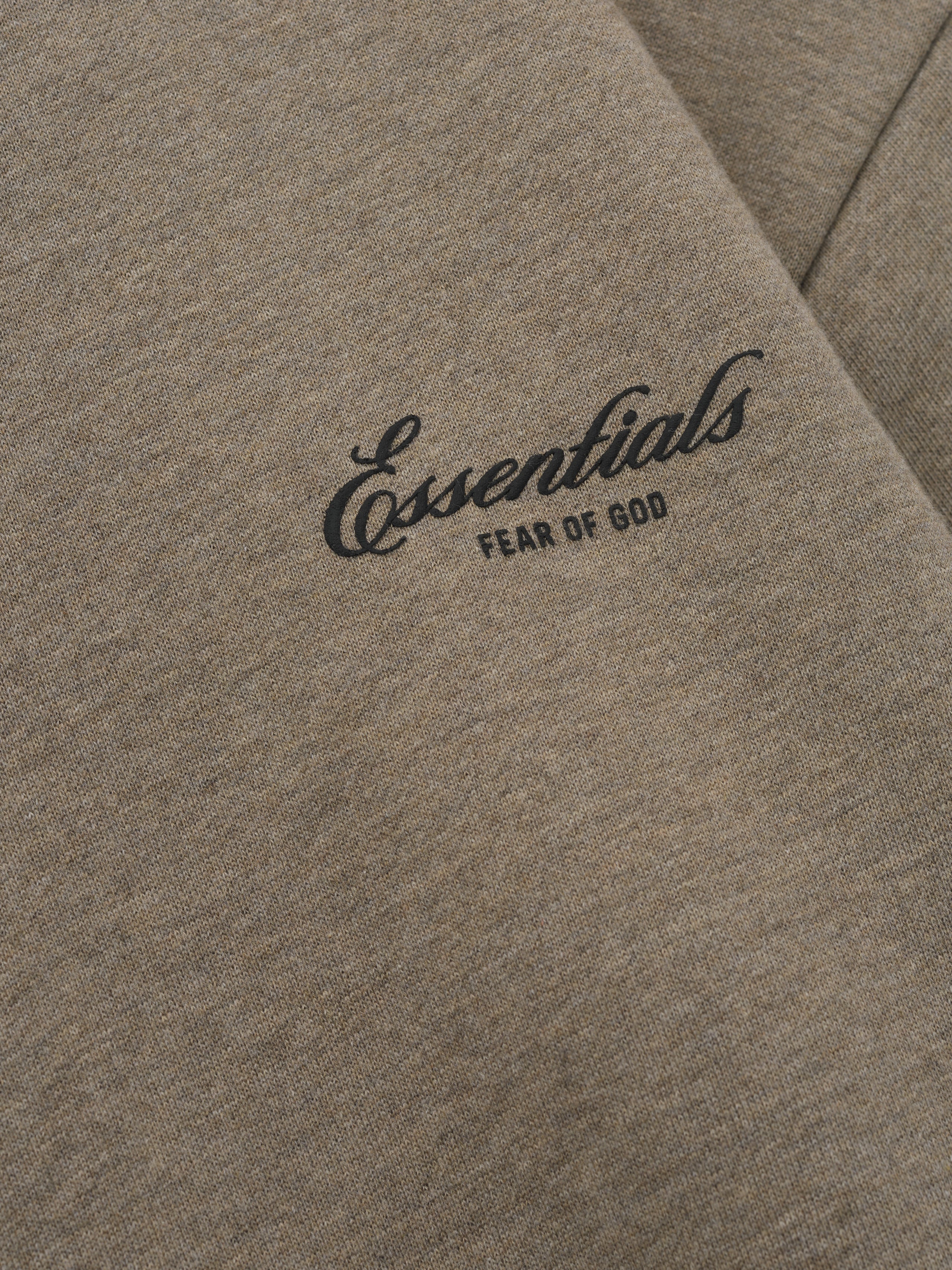 close-up of taupe core fleece fabric with Essentials Fear of God scripted logo printed on front chest panel