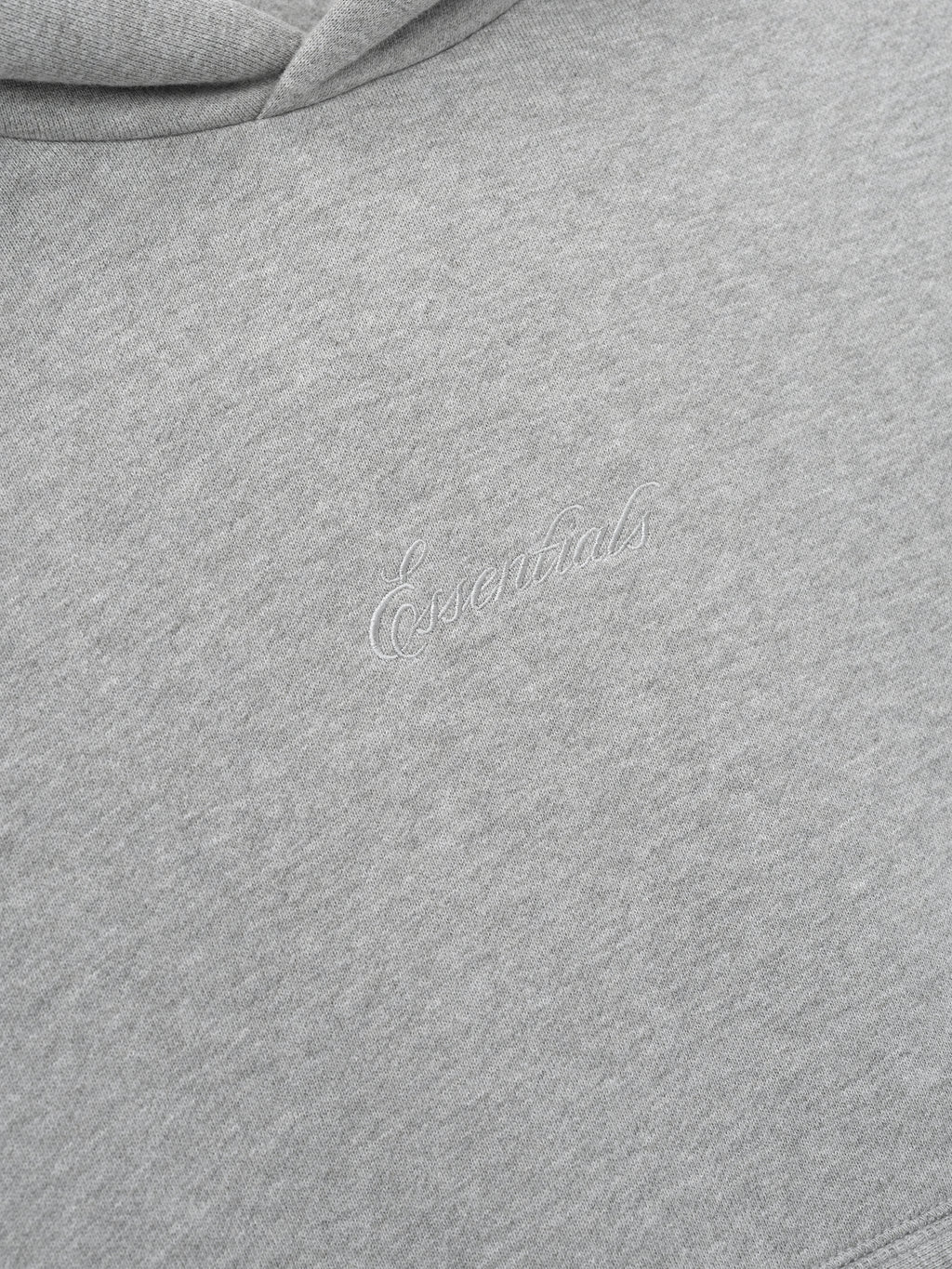 Close-up of a gray hoodie with essentials embroidery script