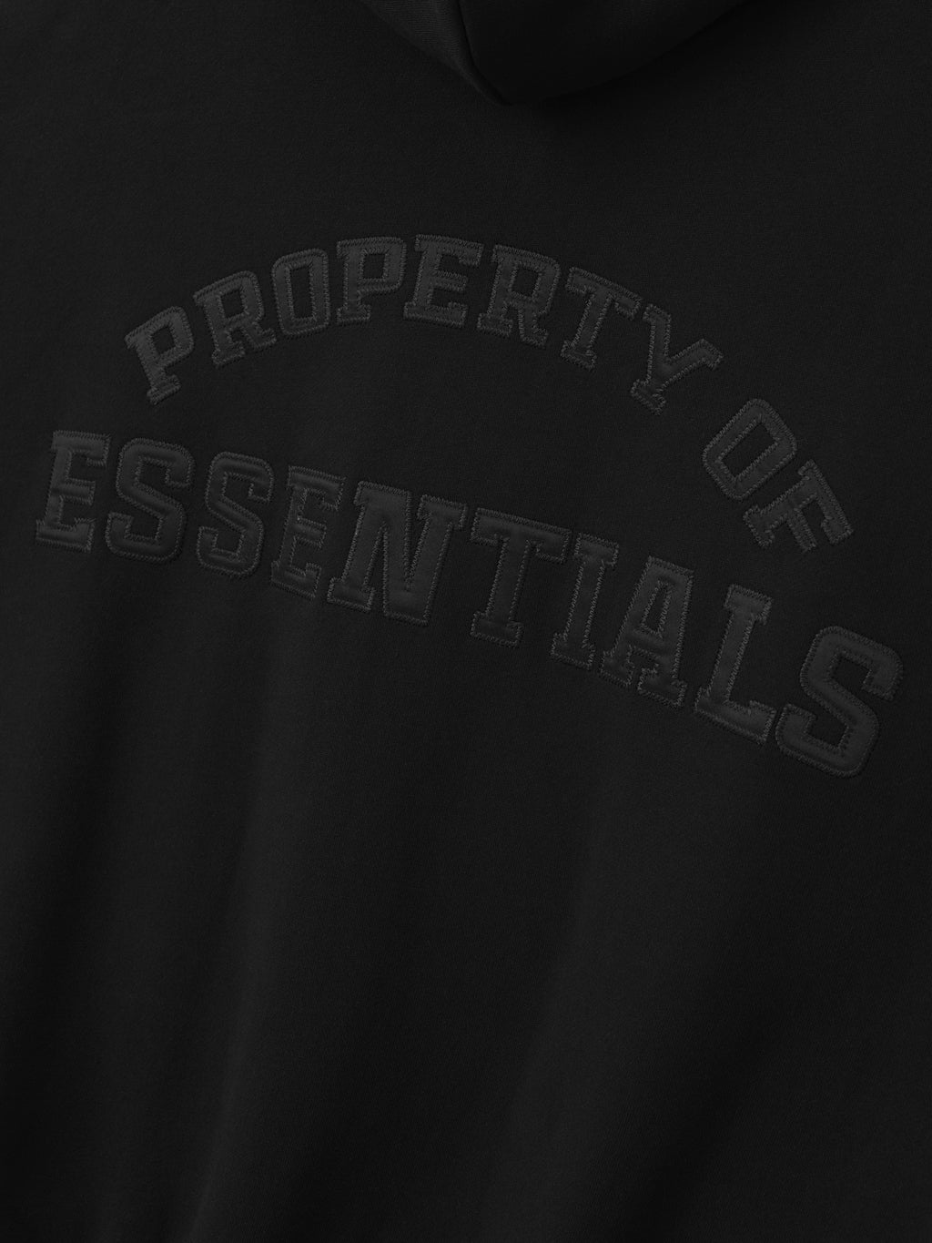 Close-up of black hoodie with raised textured text "Property of Essentials" on the chest area