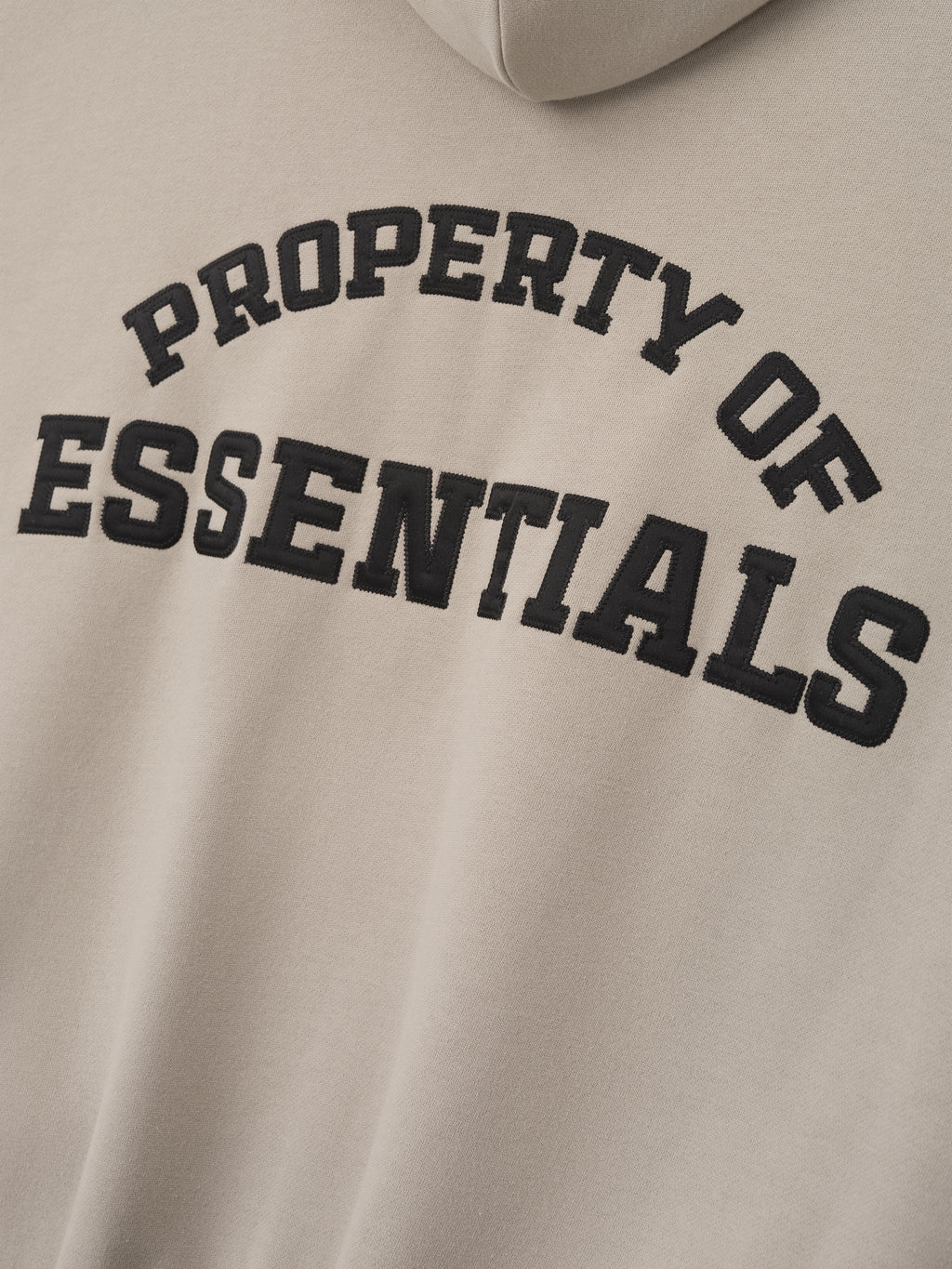 close-up of beige heavyweight fleece hoodie with black satin stitch Property of Essentials logo on back panel